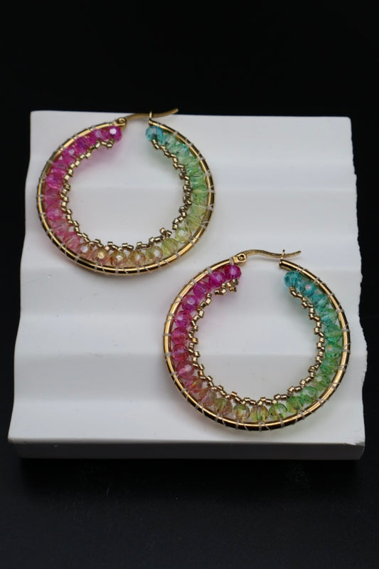 Pair of hoop earrings with gemstone beads on a white stand against a black background