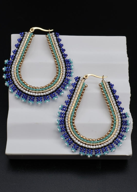 Pair of beaded earrings on a white stand with a black background