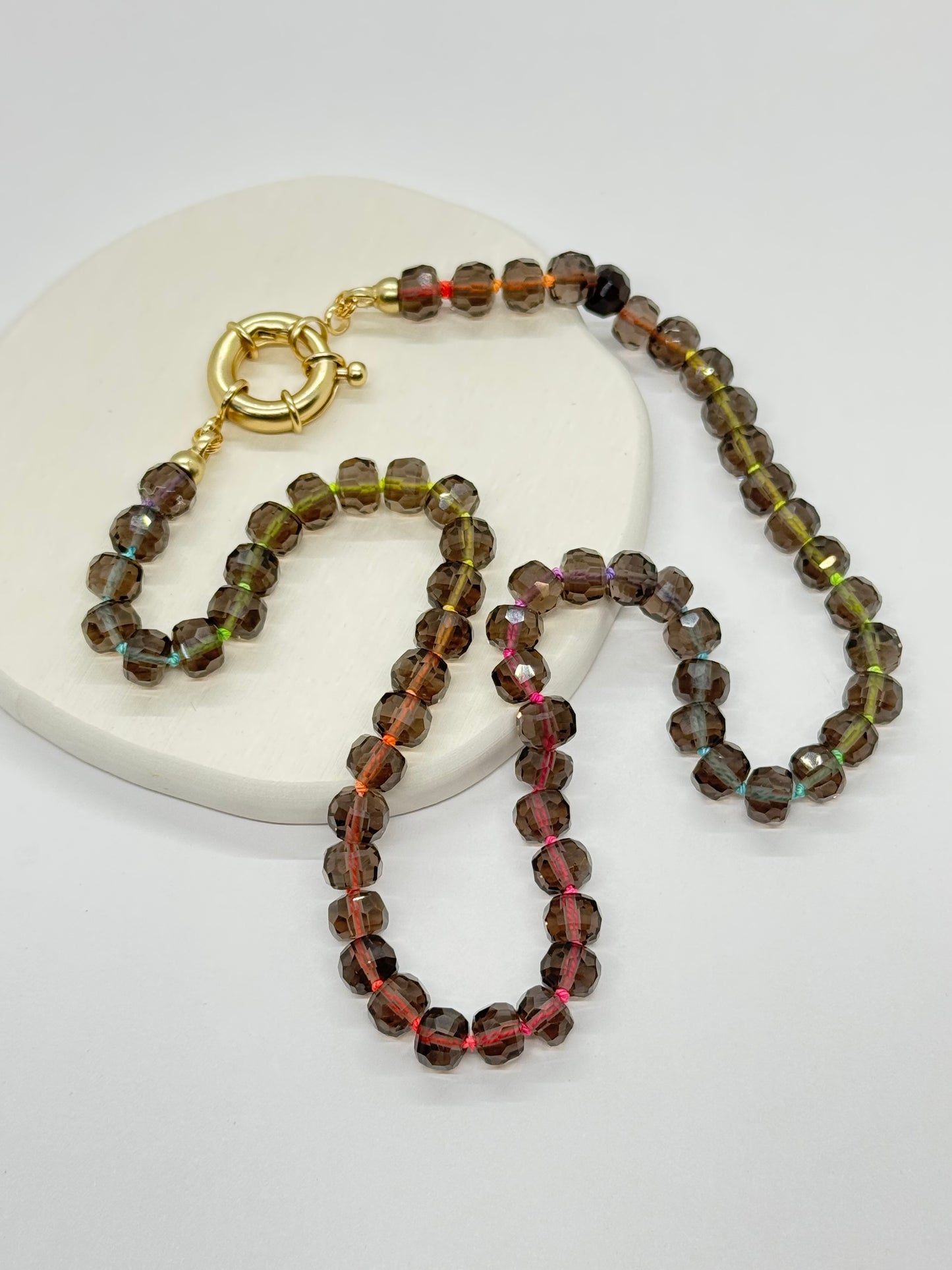 Beaded necklace with a gold clasp on a white surface