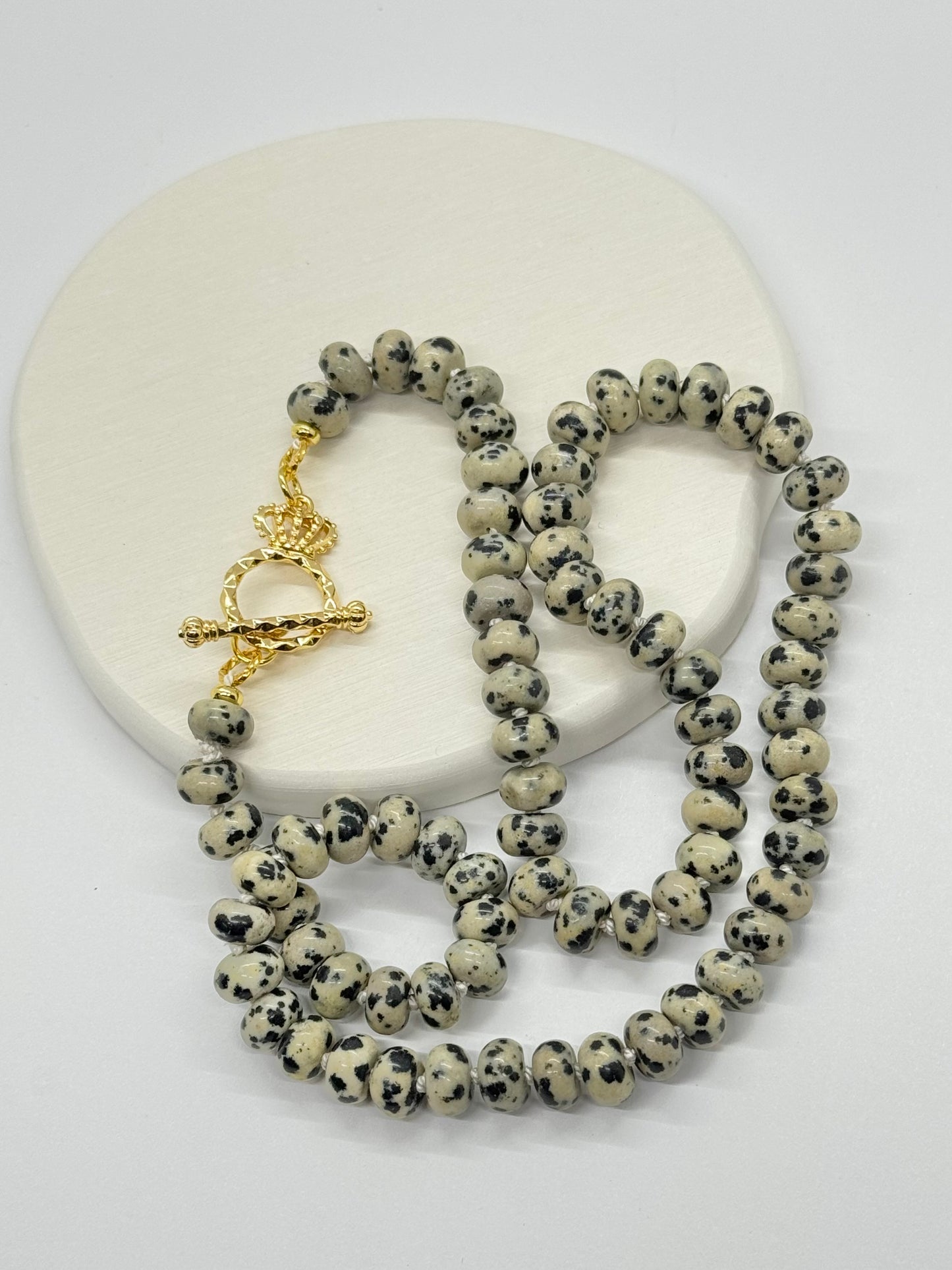 Necklace with dalmatian jasper beads and gold clasp on a white background