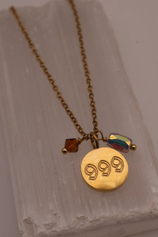 Gold necklace with a '999' pendant on a textured surface