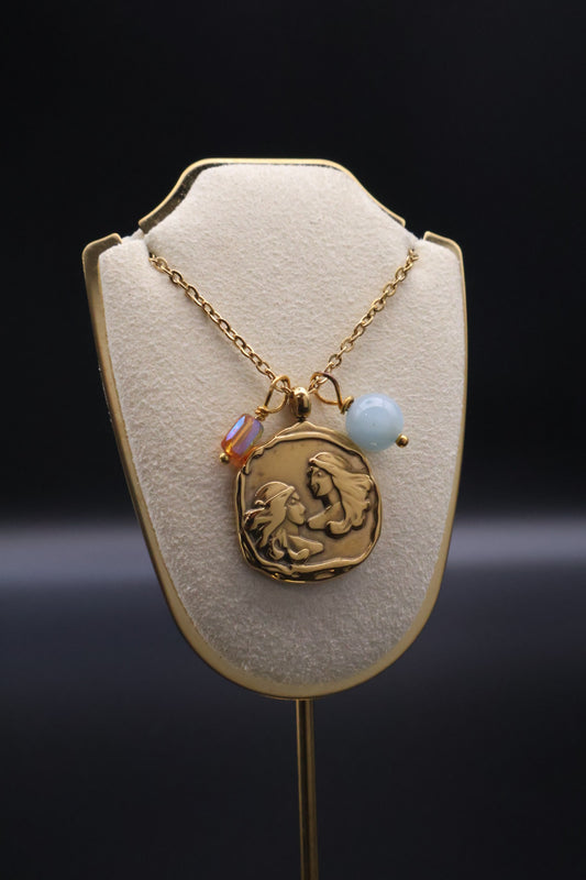 Gold necklace with a pendant on a display stand against a dark background