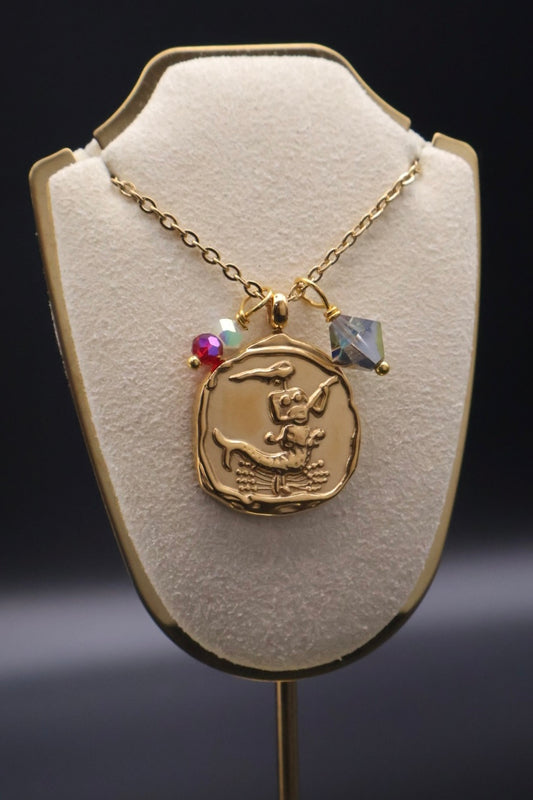 Gold necklace with a pendant on a white display stand against a dark background