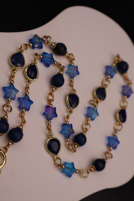 Necklace with blue star-shaped beads and gold chain on a white background