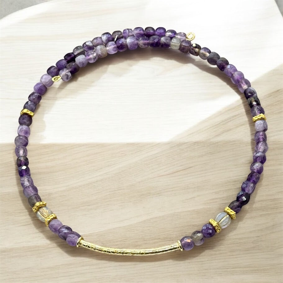 A flexible choker adorned with purple stones and gold accents, featuring an elegant and timeless design.