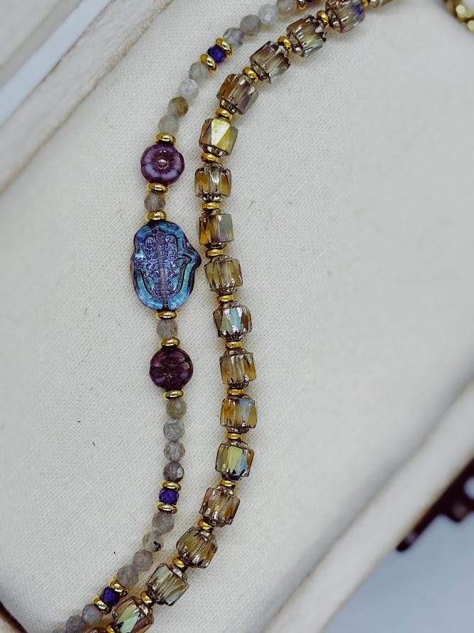 a bracelet with labradorite beads, a hamsa hand focal, and two purple flower beads and a bracelet with baroque styled beads.