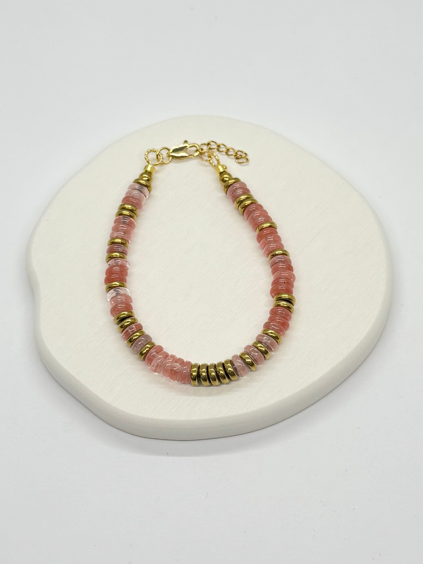 Bracelet with pink and gold beads on a white surface