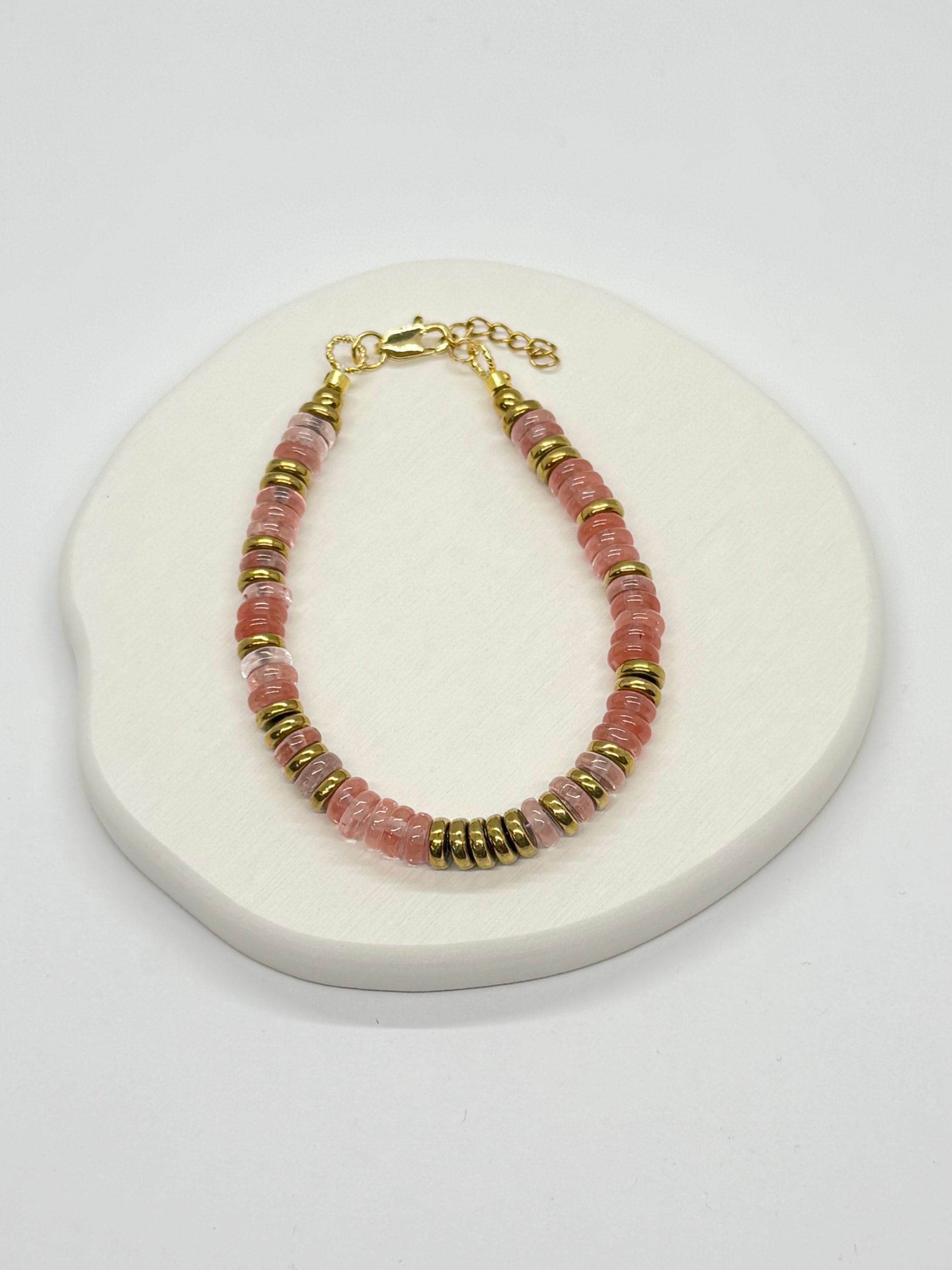 Bracelet with pink and gold beads on a white surface