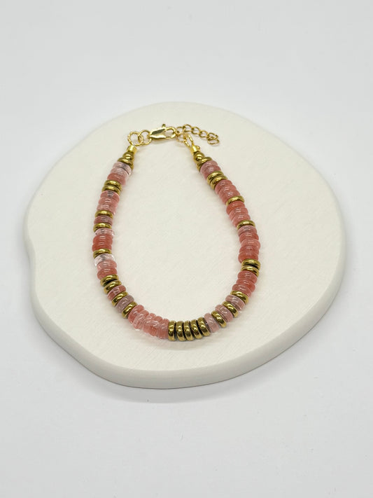 Bracelet with pink and gold beads on a white surface