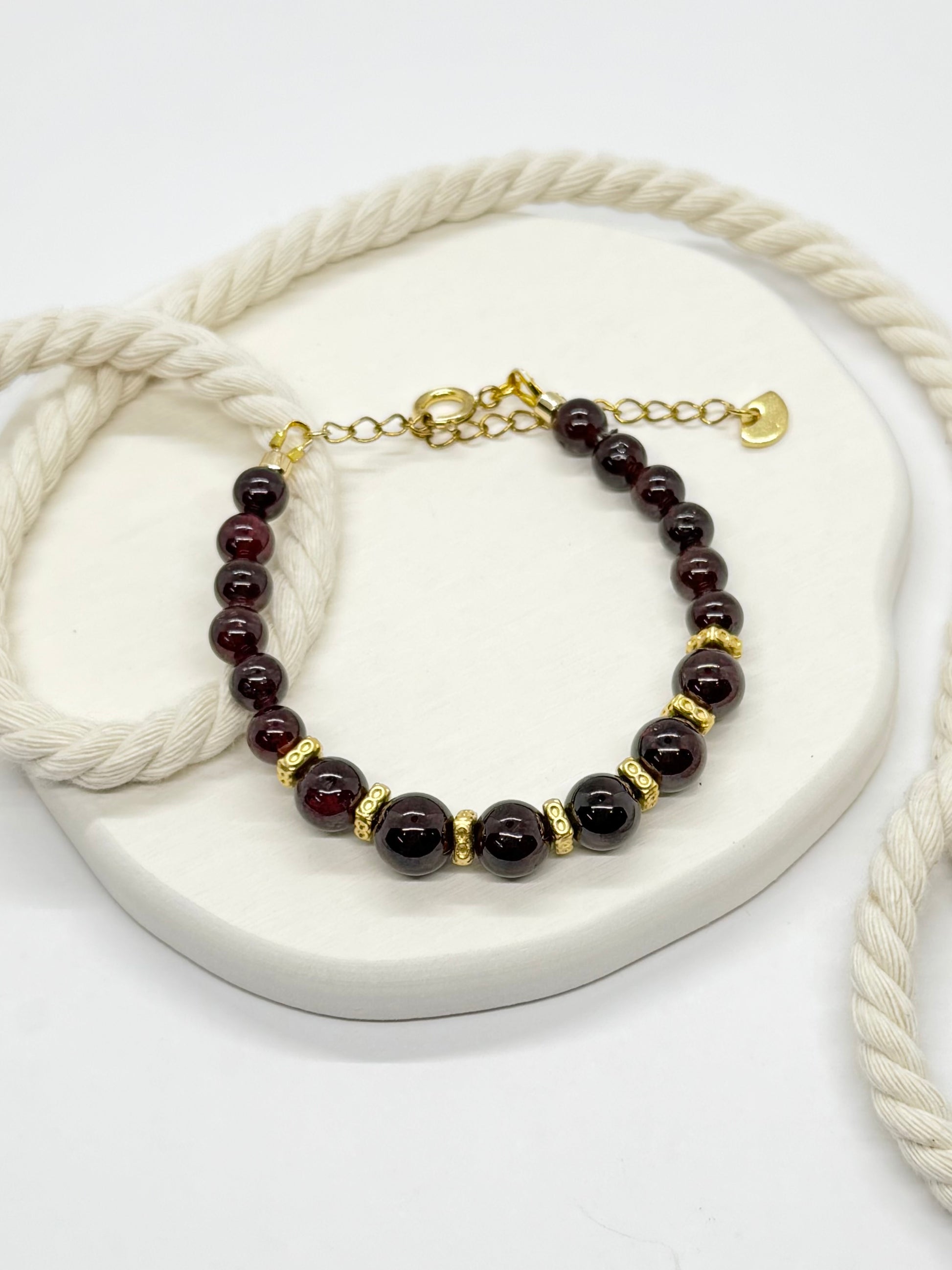 Bracelet with dark beads and gold accents on a white surface