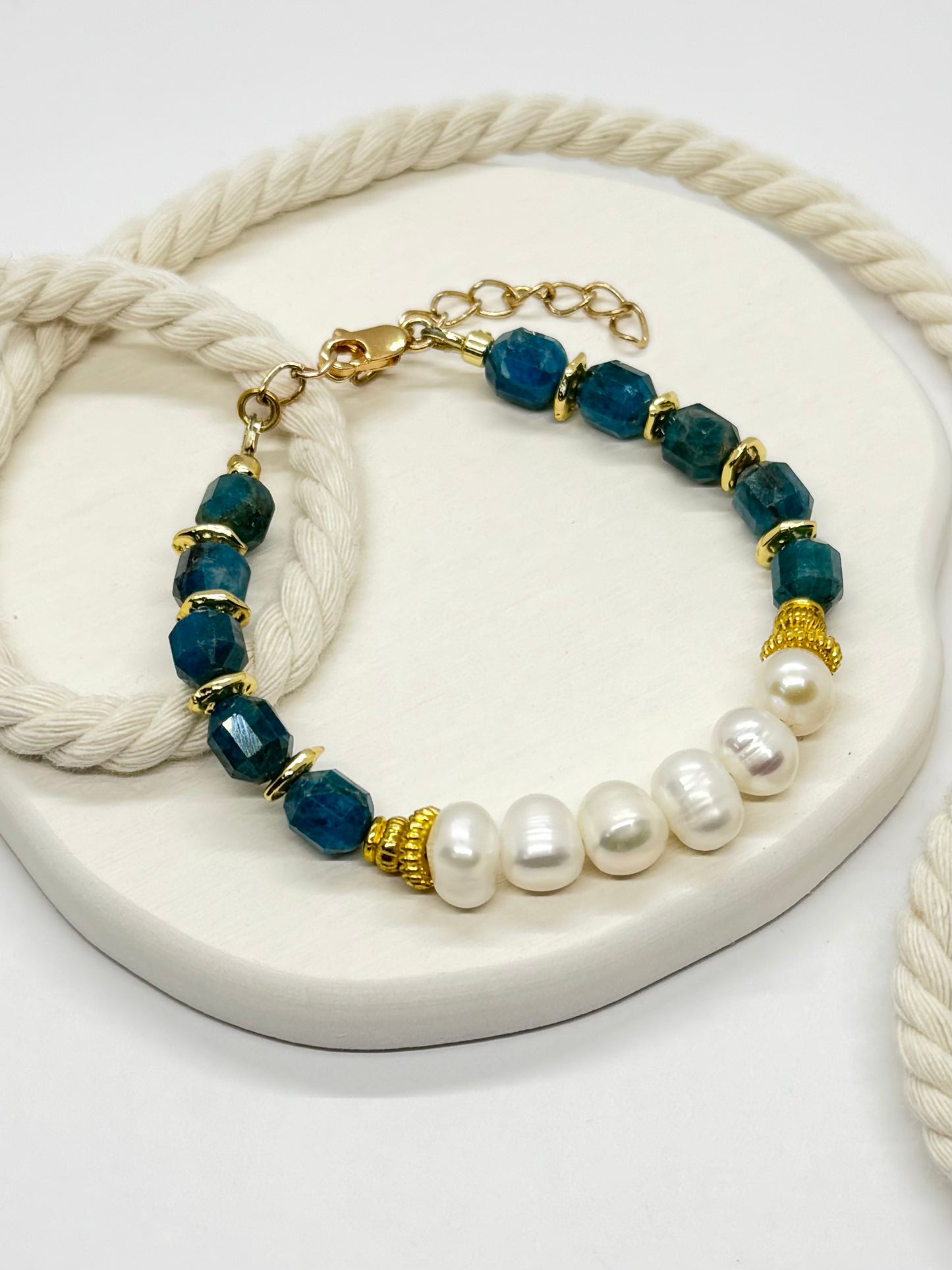 Bracelet with blue beads, pearls, and gold accents on a white surface