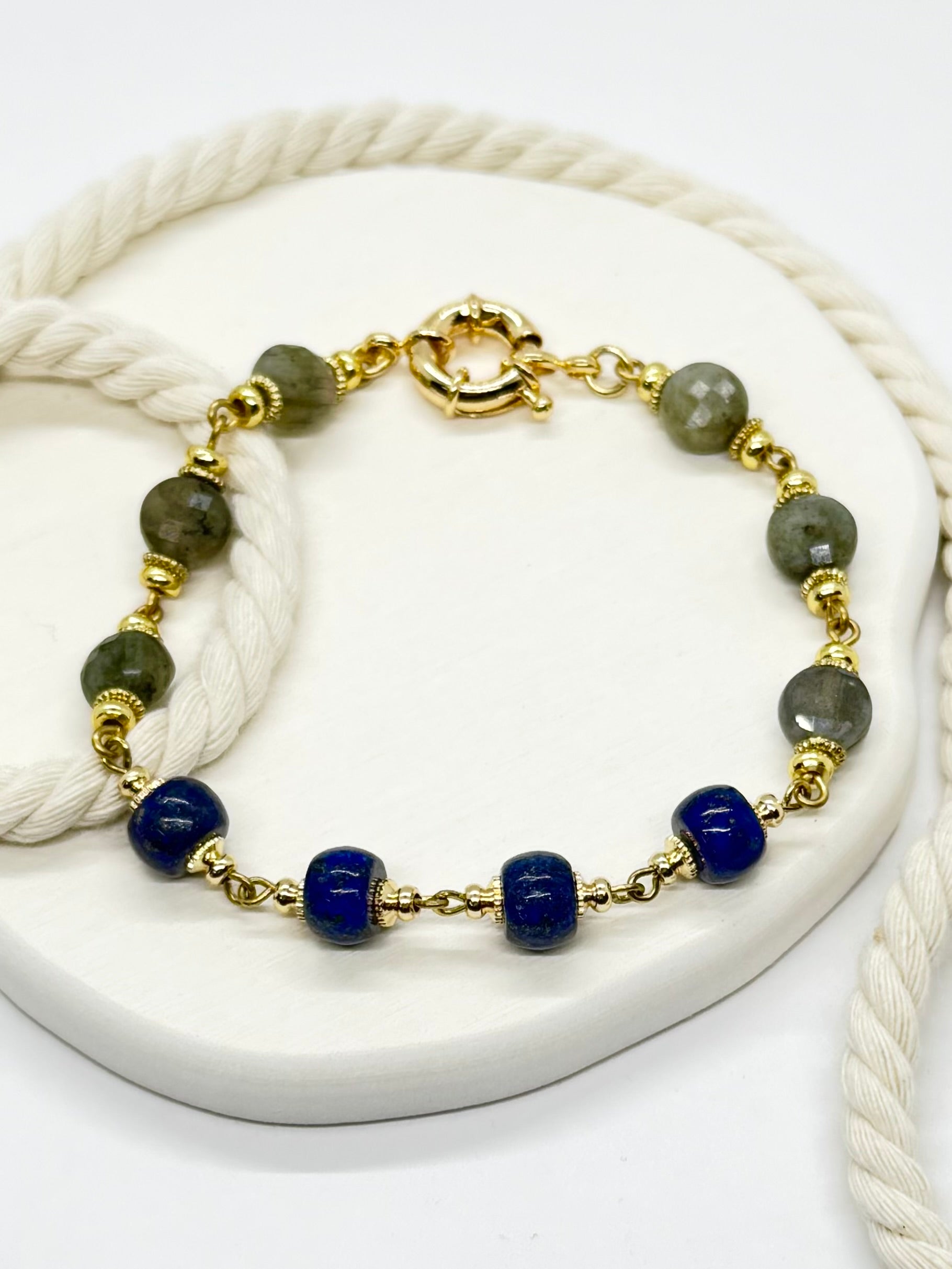 Bracelet with gold, blue, and green beads on a white surface