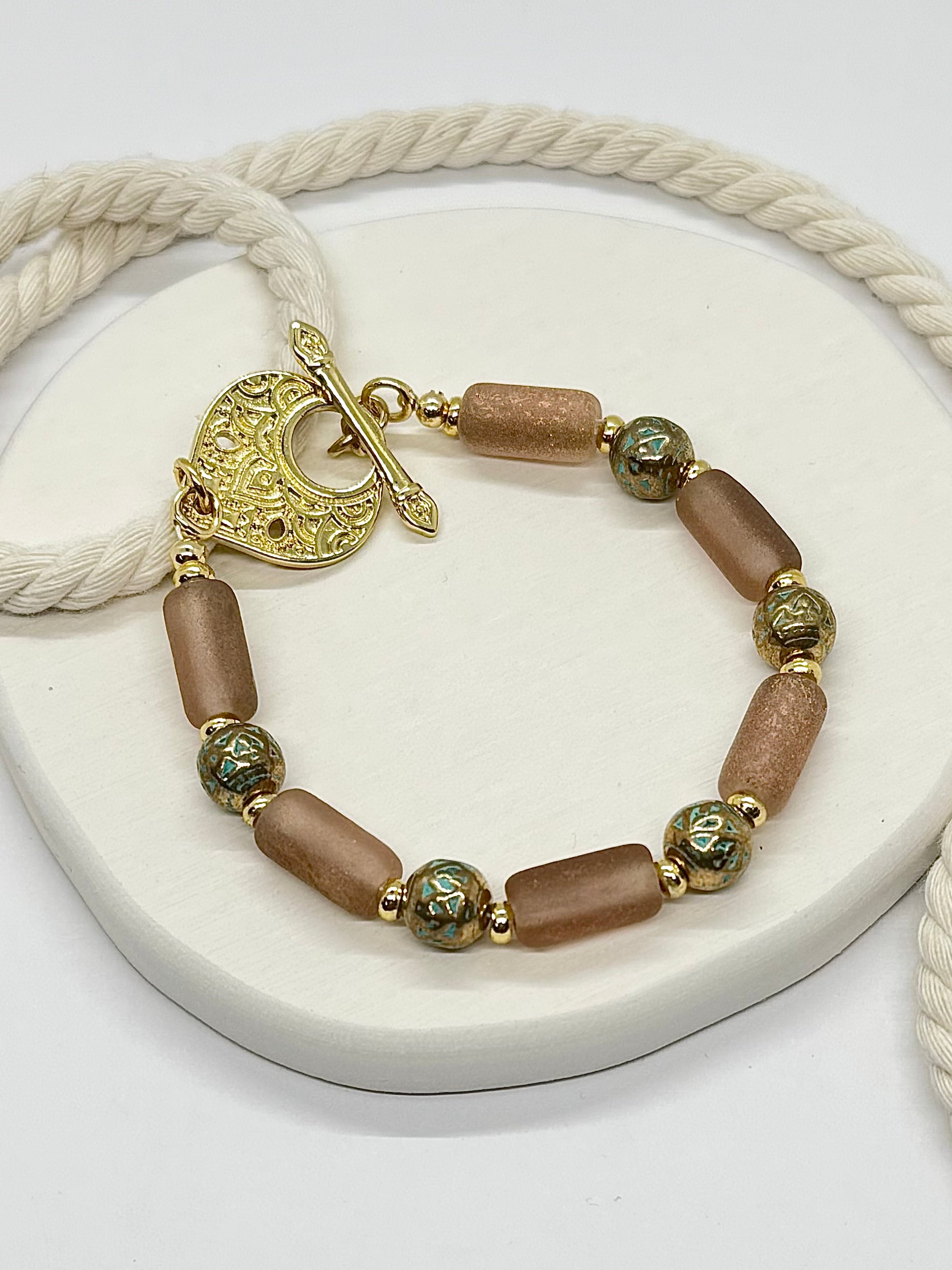 Bracelet with brown beads and gold accents on a white surface