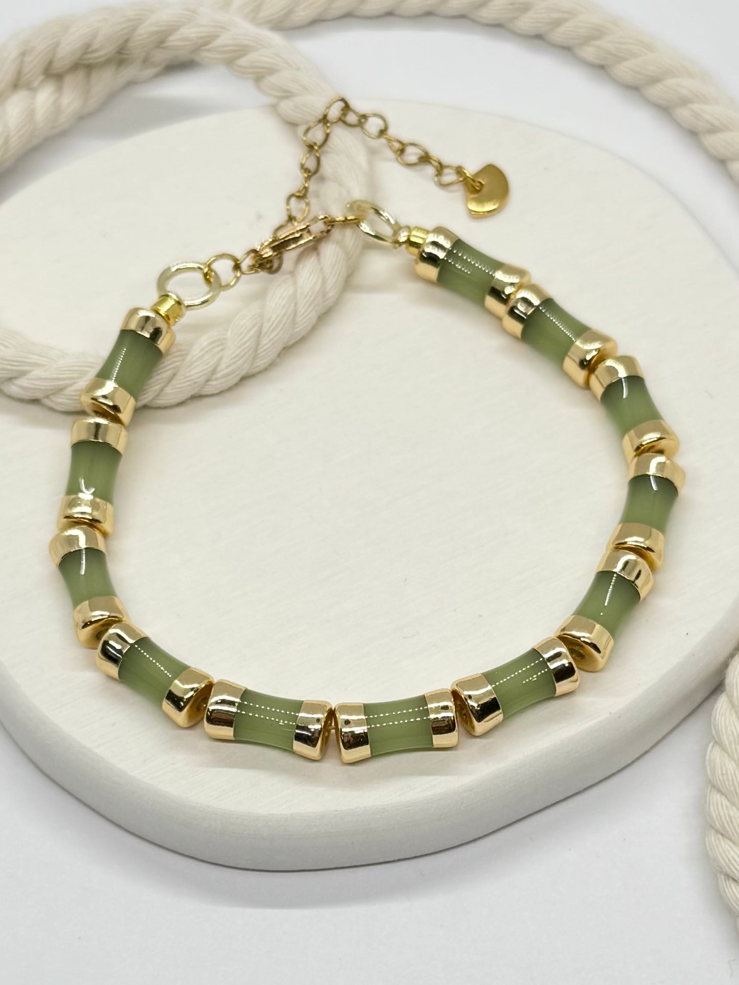Bracelet with green beads and gold accents on a white surface