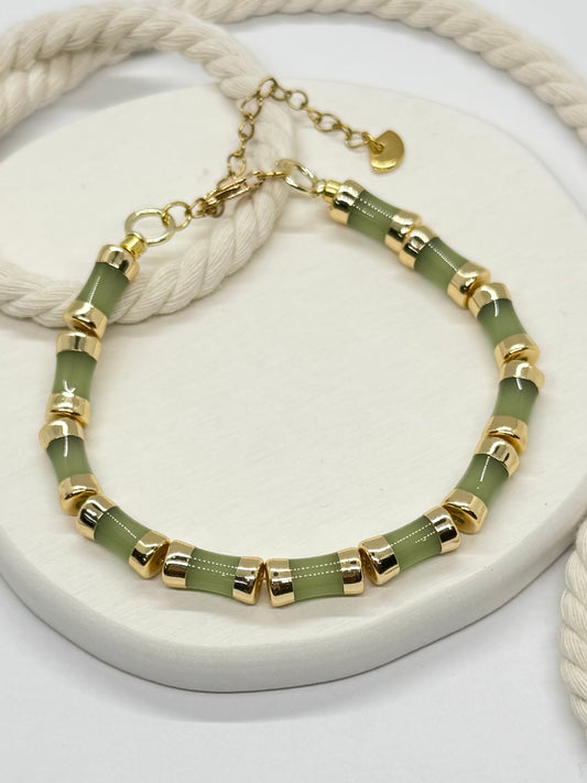 Bracelet with green beads and gold accents on a white surface