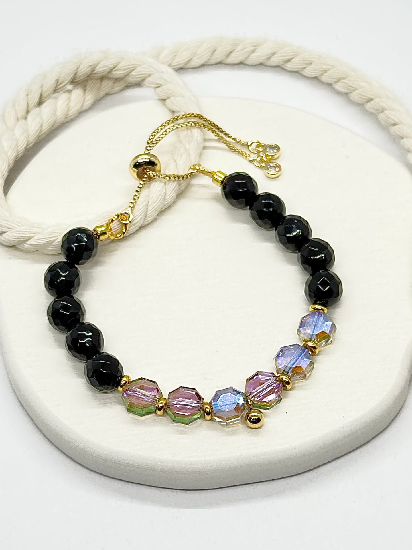 Bracelet with black beads and colorful crystals on a white surface