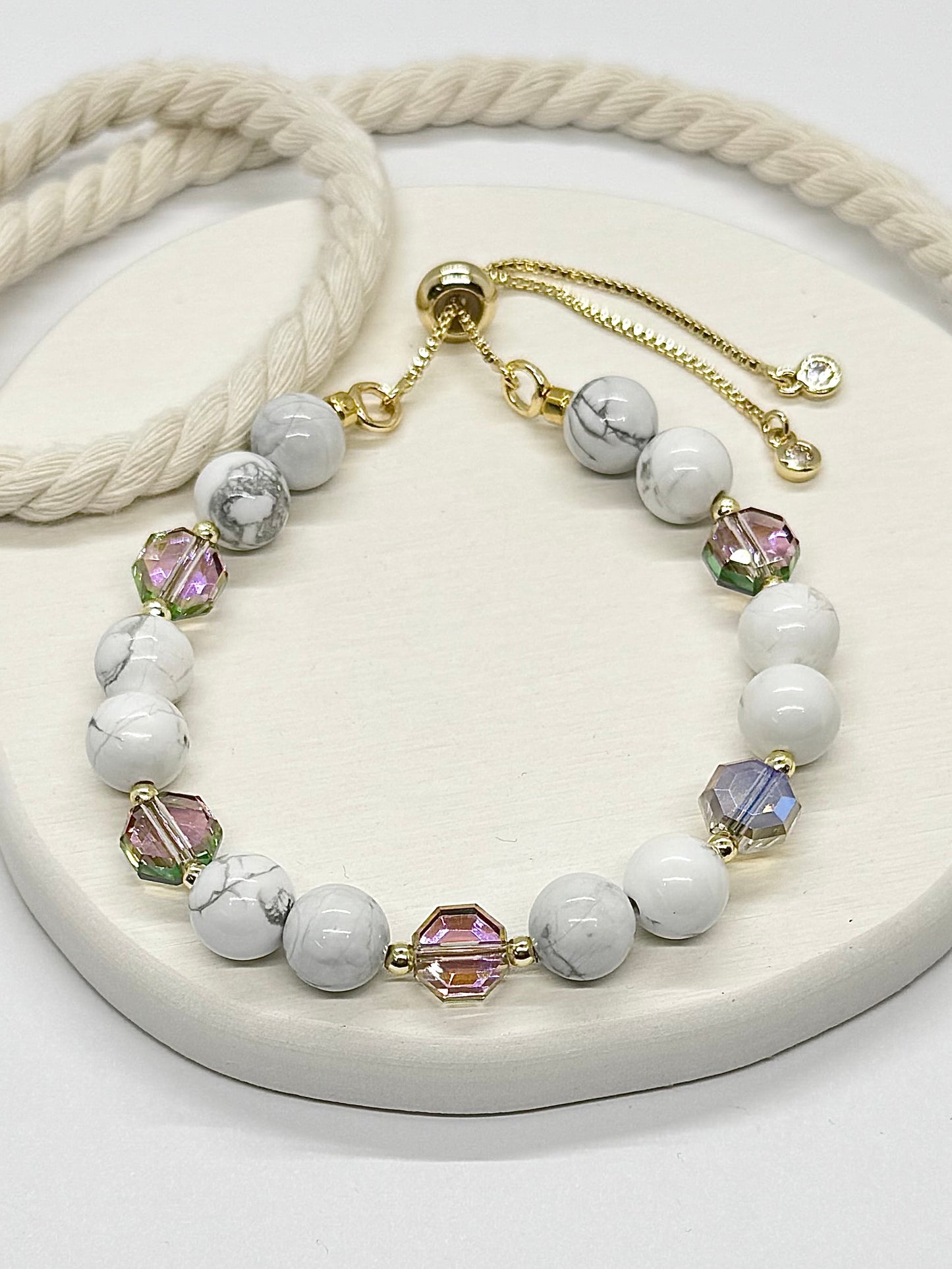 Necklace with white beads and colorful crystals on a white surface
