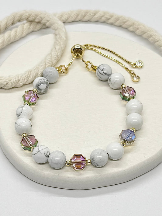 Necklace with white beads and colorful crystals on a white surface