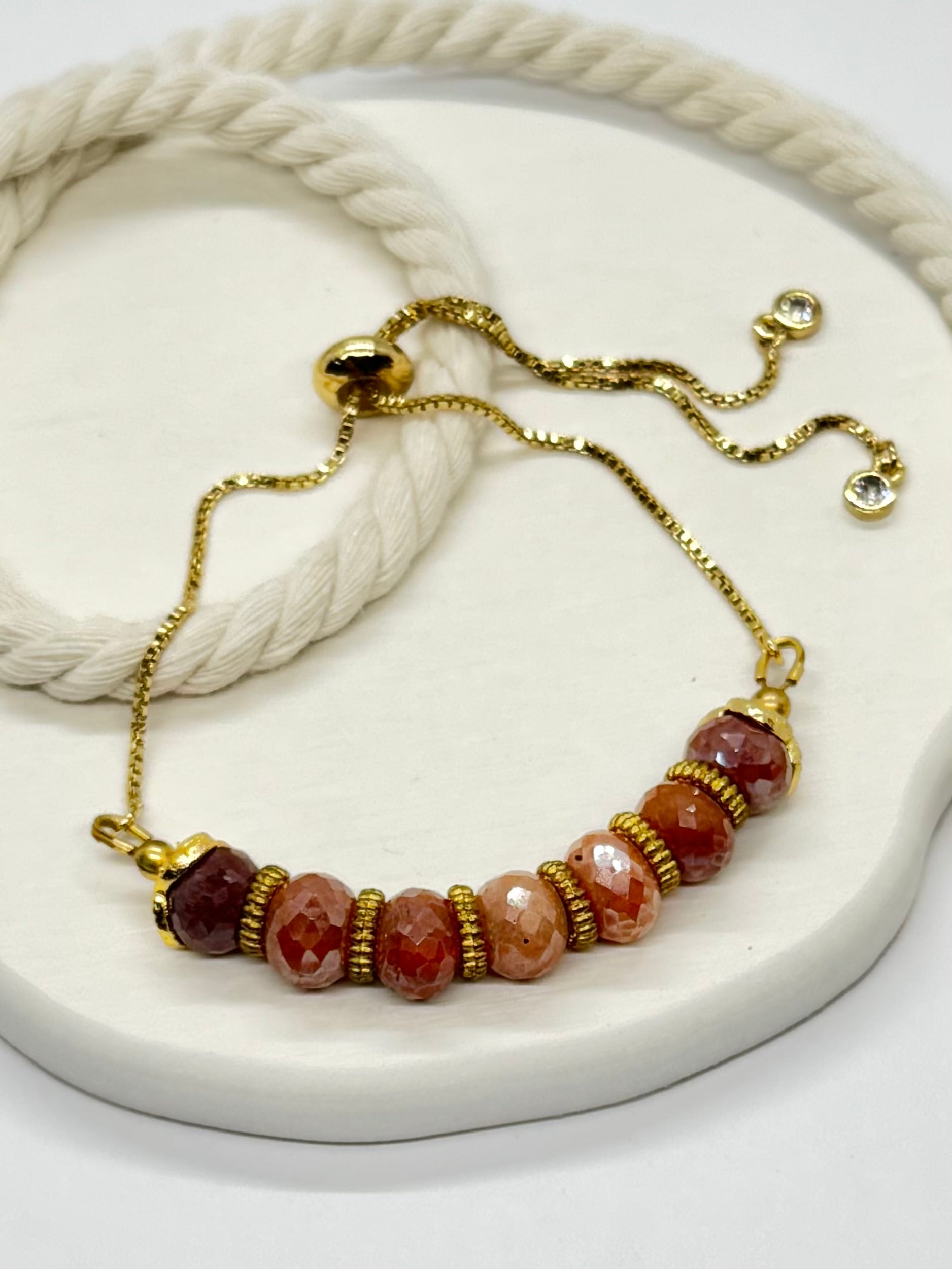 Bracelet with gold chain and multicolored beads on a white surface