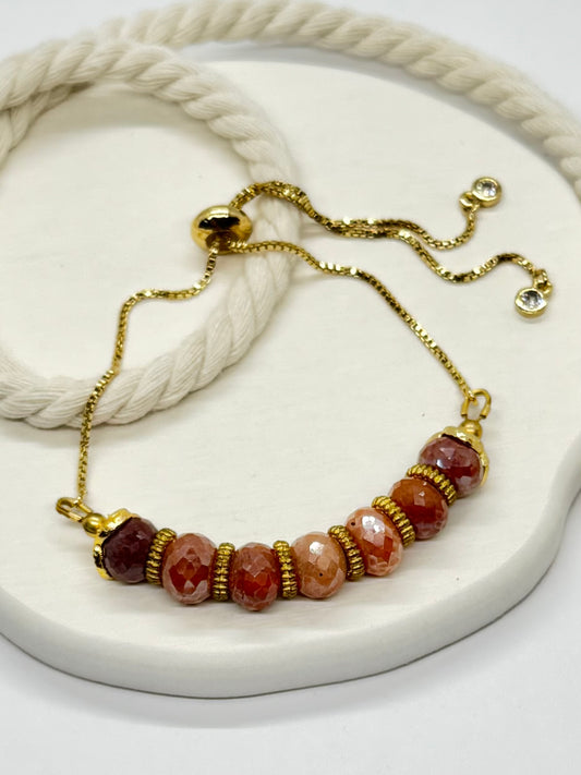 Bracelet with gold chain and multicolored beads on a white surface