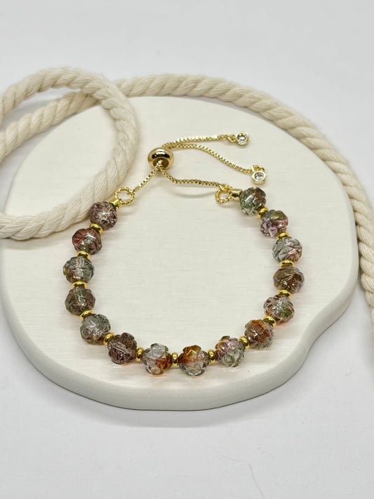 Bracelet with multicolored beads and gold accents on a white surface