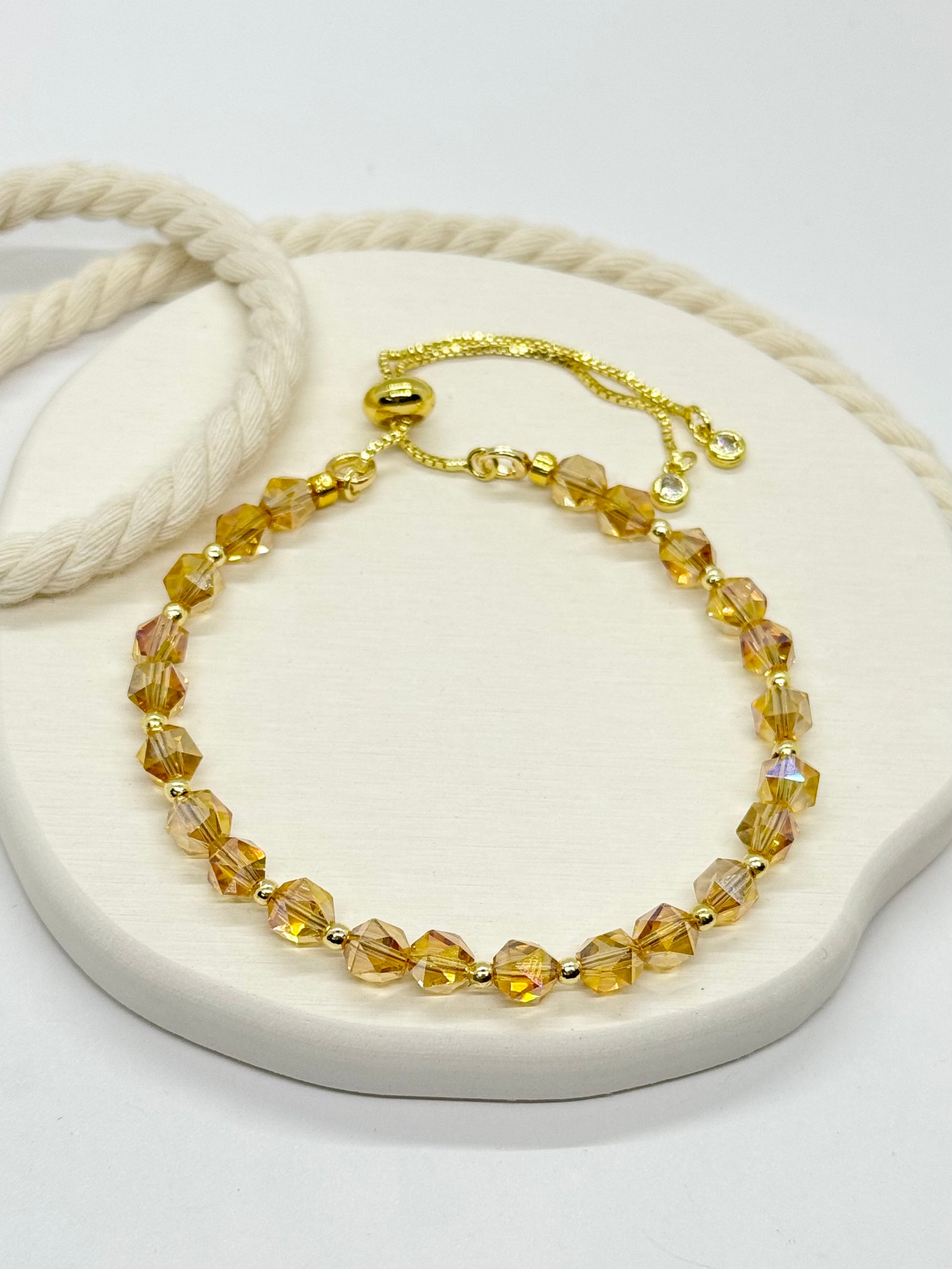 Gold bracelet with yellow beads on a white surface