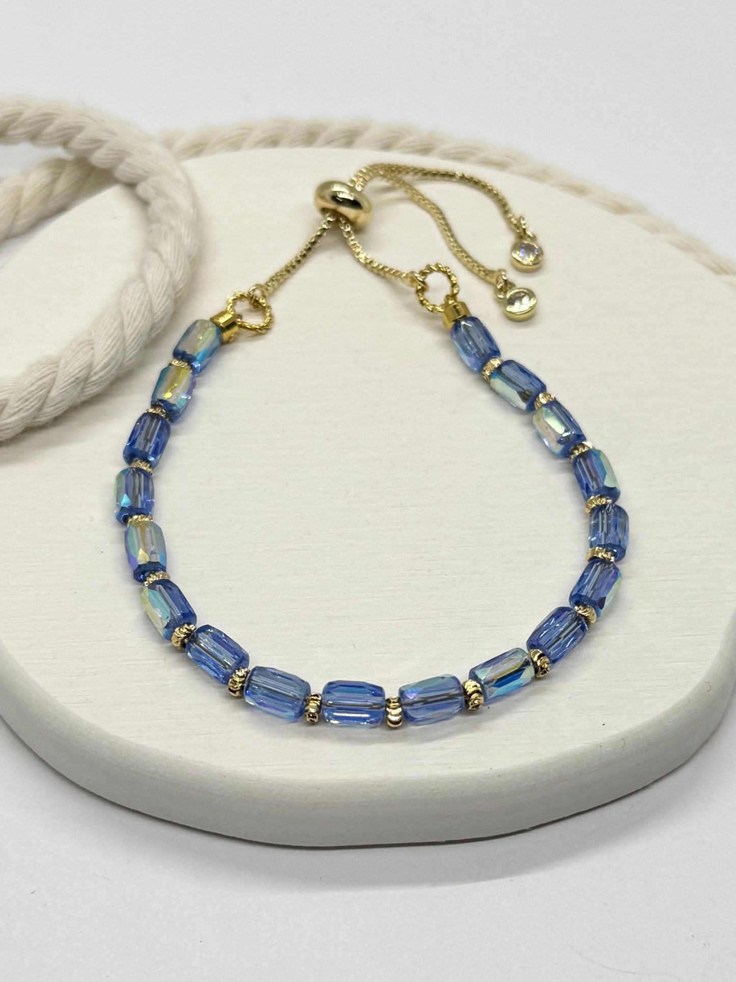 Blue beaded bracelet with gold accents on a white surface