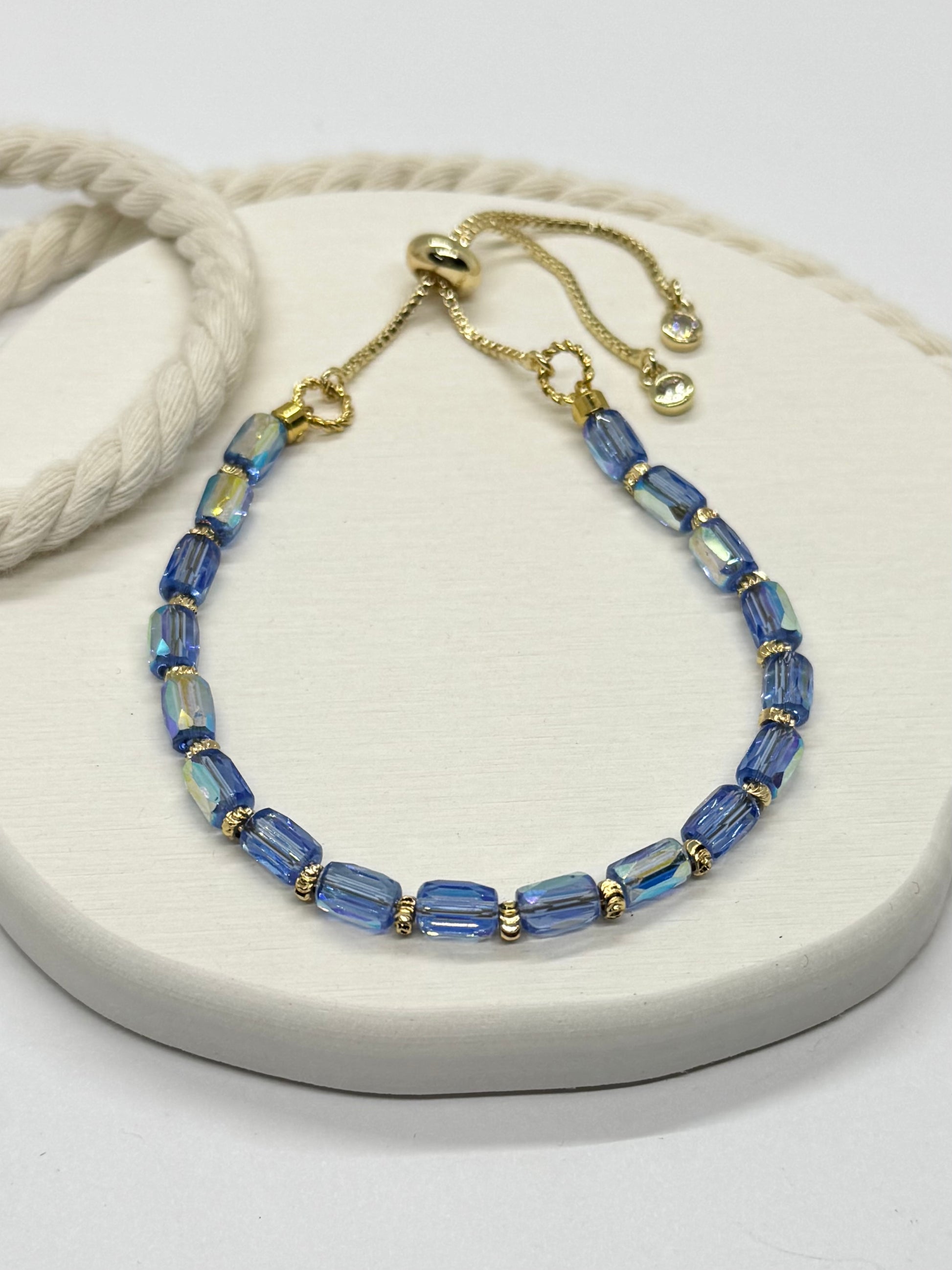Blue beaded bracelet with gold accents on a white surface