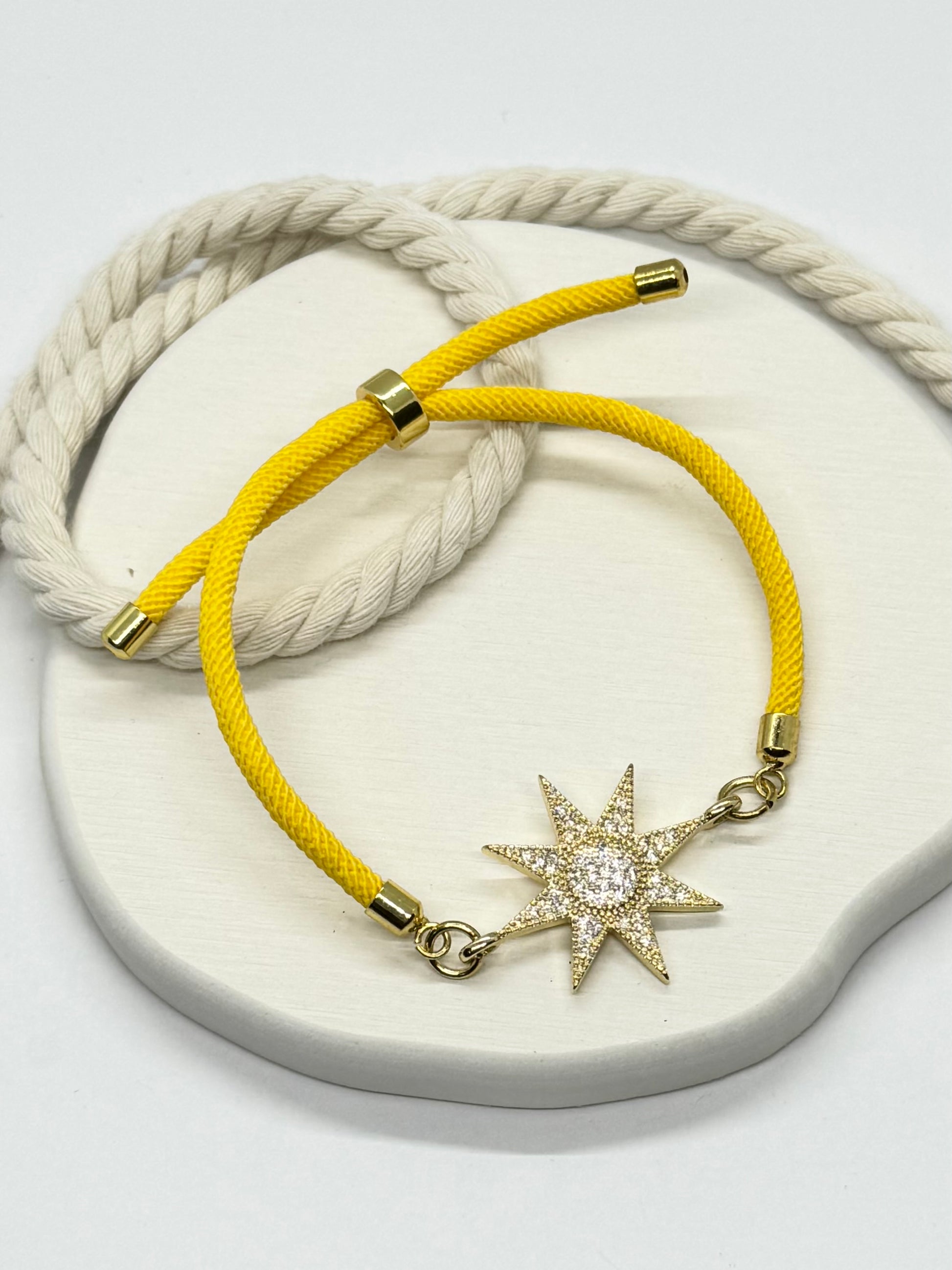 Yellow bracelet with a star-shaped charm on a white stone surface