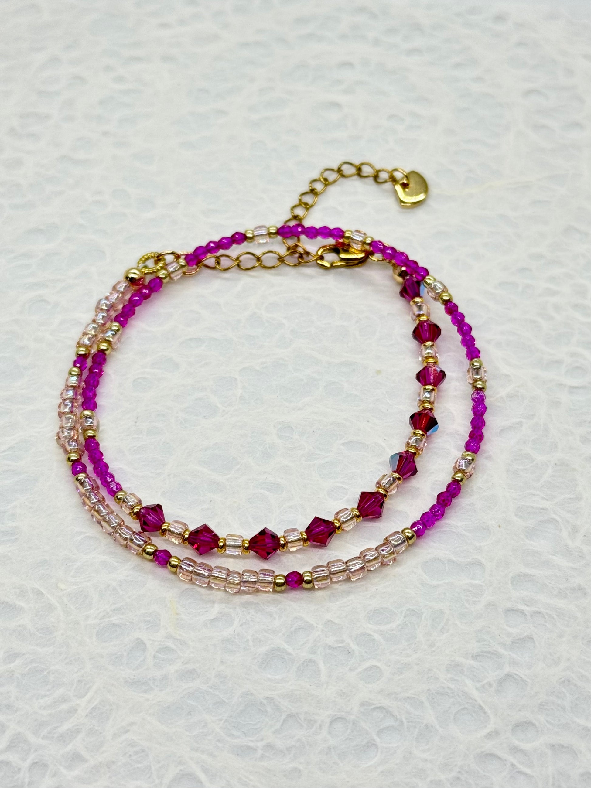Multistrand beaded bracelet with pink and gold beads on a light gray background