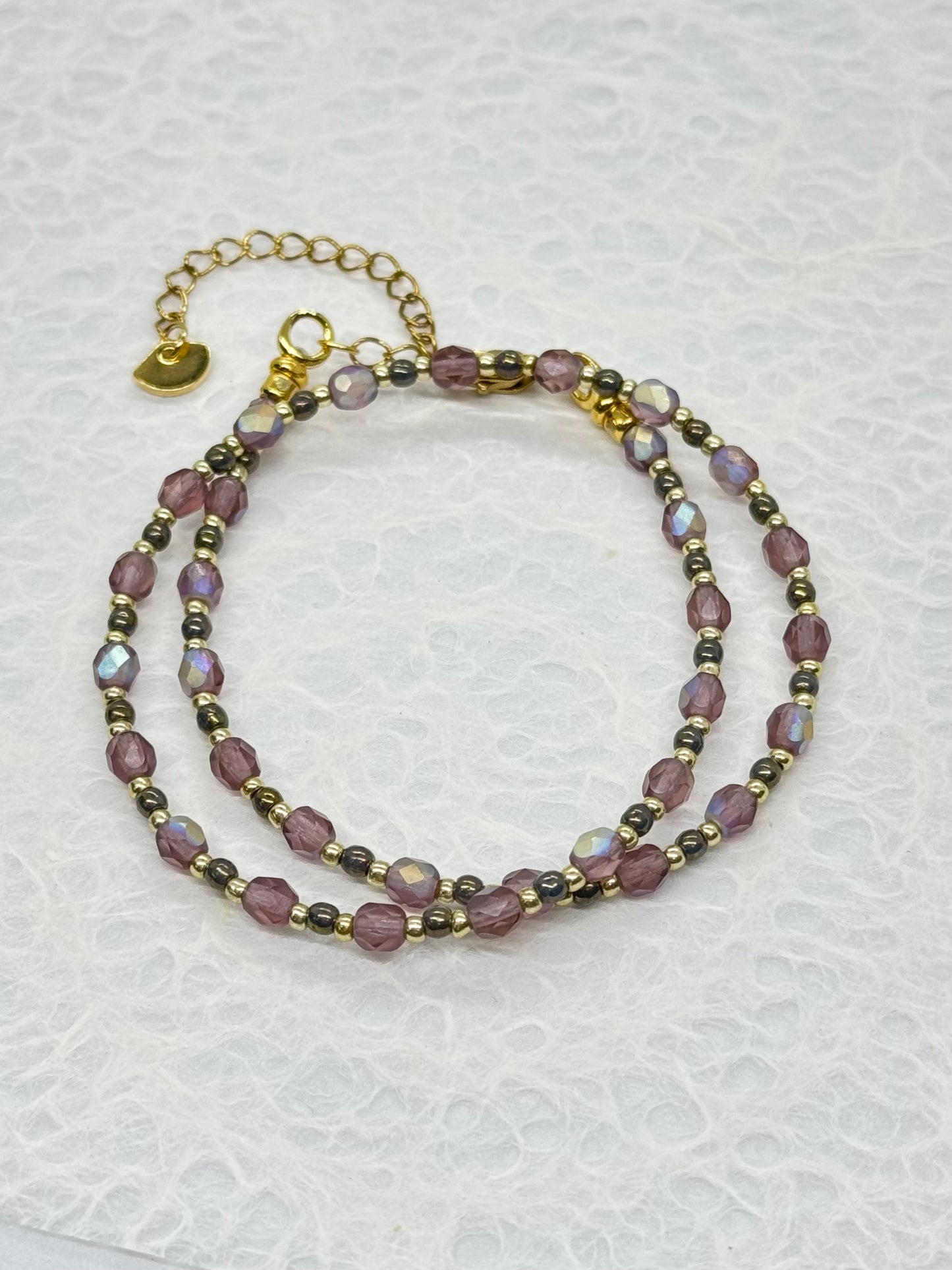 Two beaded bracelets on a textured white surface
