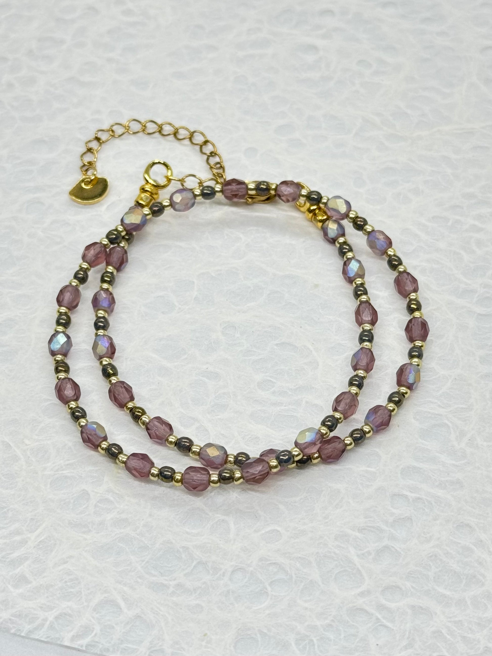 Two beaded bracelets on a textured white surface