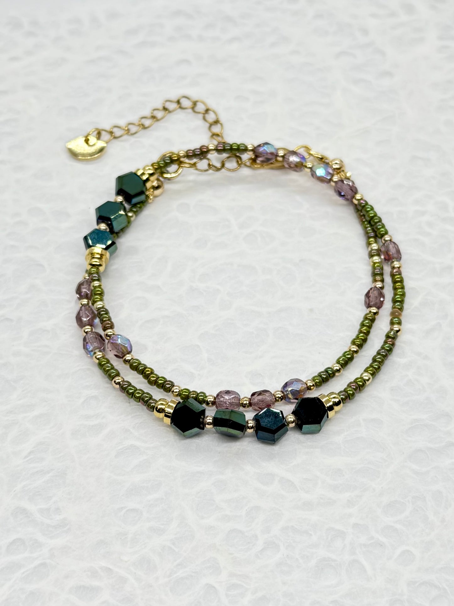 Multistrand beaded bracelet with green and purple beads on a white background