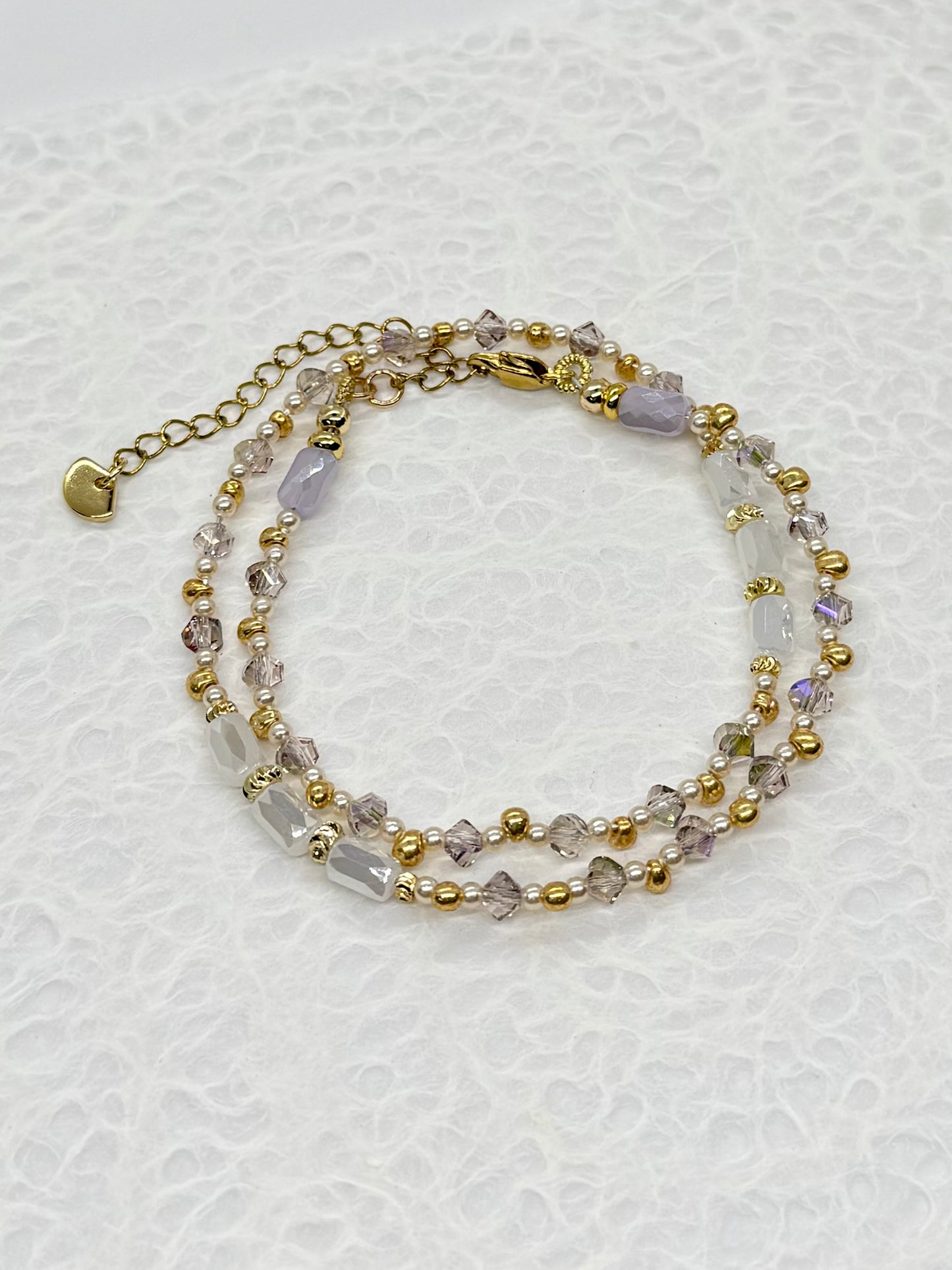 Multistrand beaded bracelet with gold accents on a textured white background