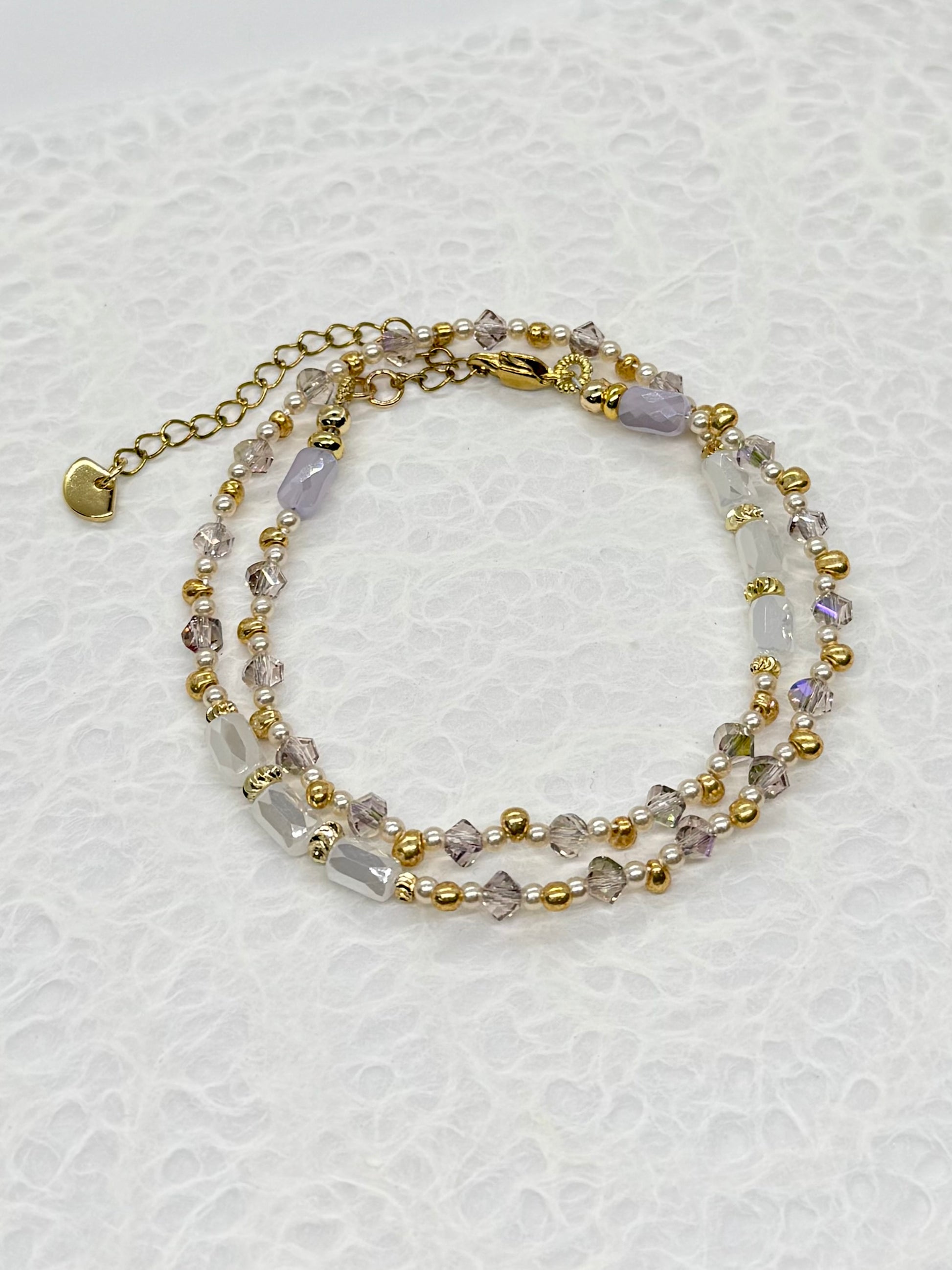 Multistrand beaded bracelet with gold accents on a textured white background