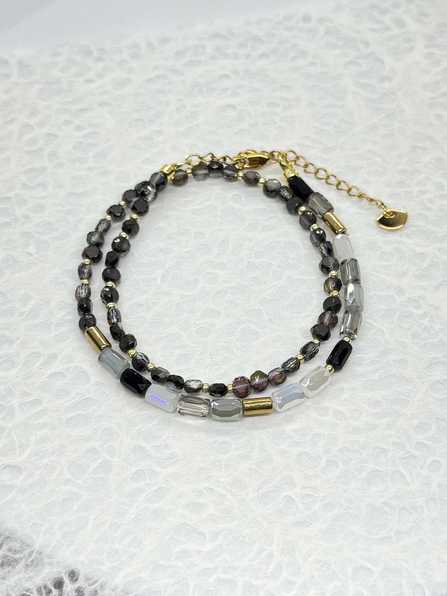 Beaded bracelet with gold accents on a textured white background