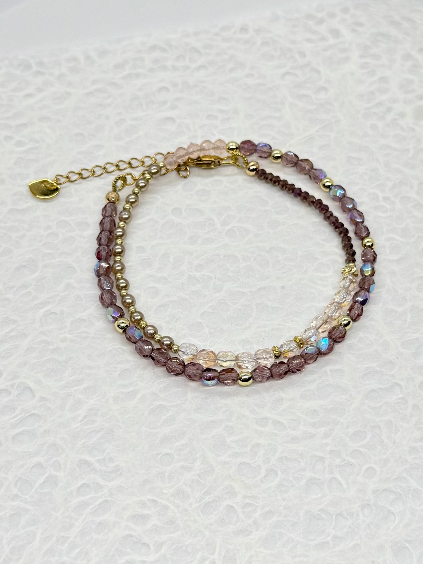 Multistrand beaded bracelet with gold chain on a white background