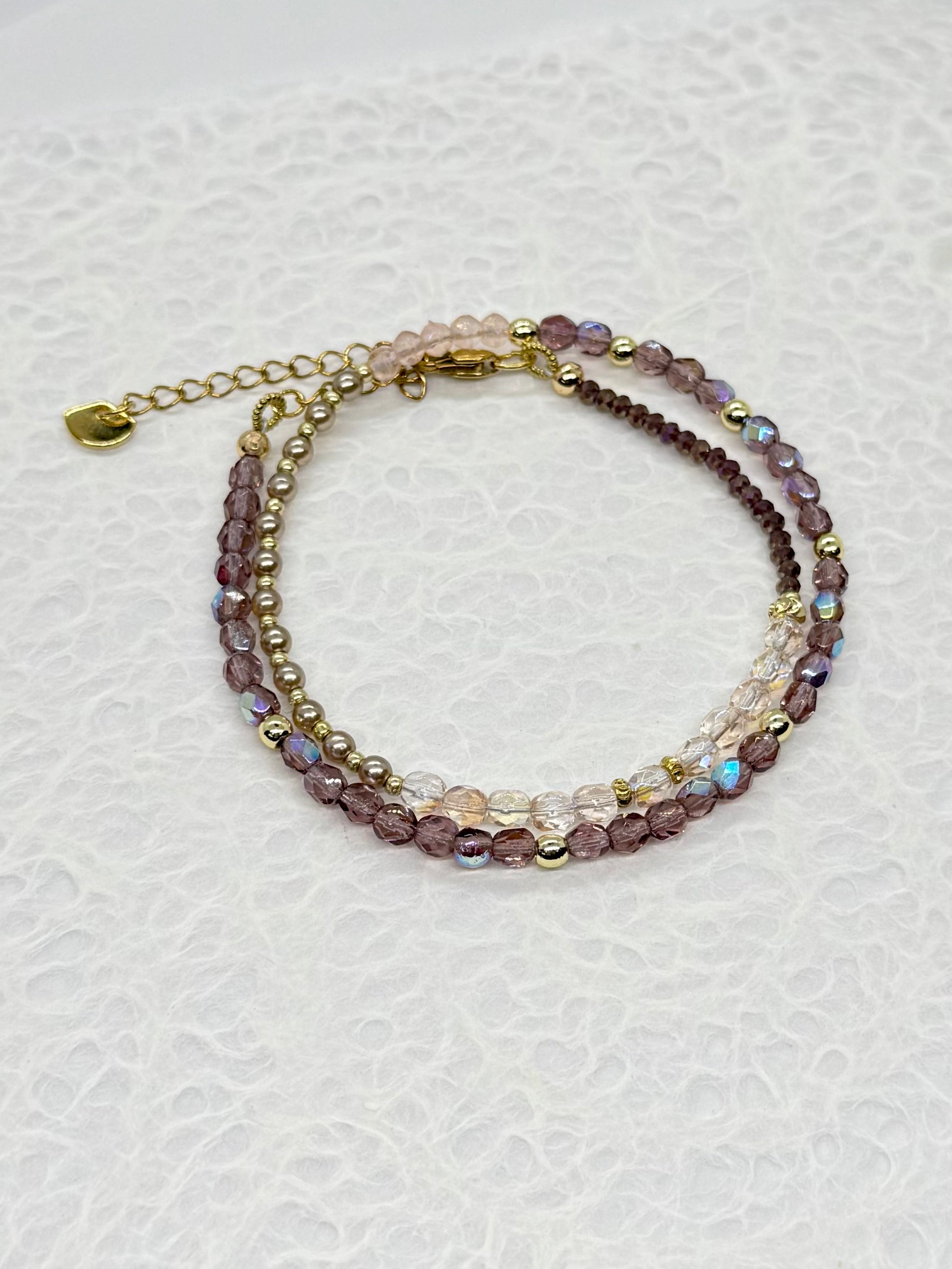 Multistrand beaded bracelet with gold chain on a white background