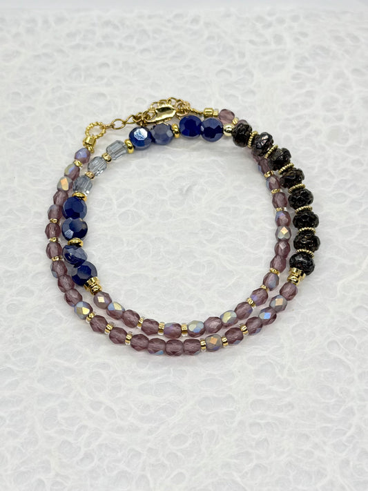 Multistrand beaded bracelet with purple, black, and gold beads on a textured white background