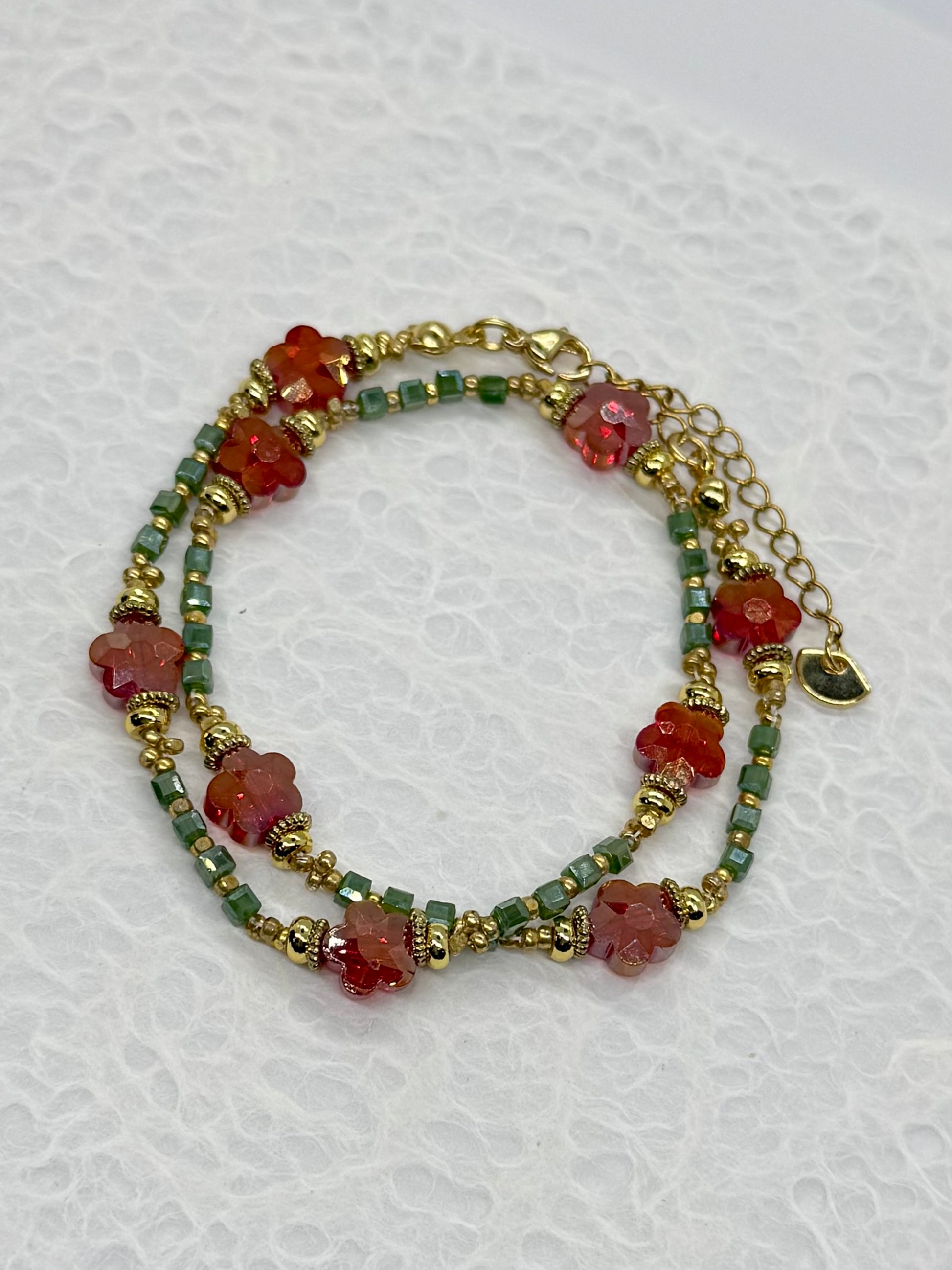 Multistrand bracelet with red and green beads on a white background