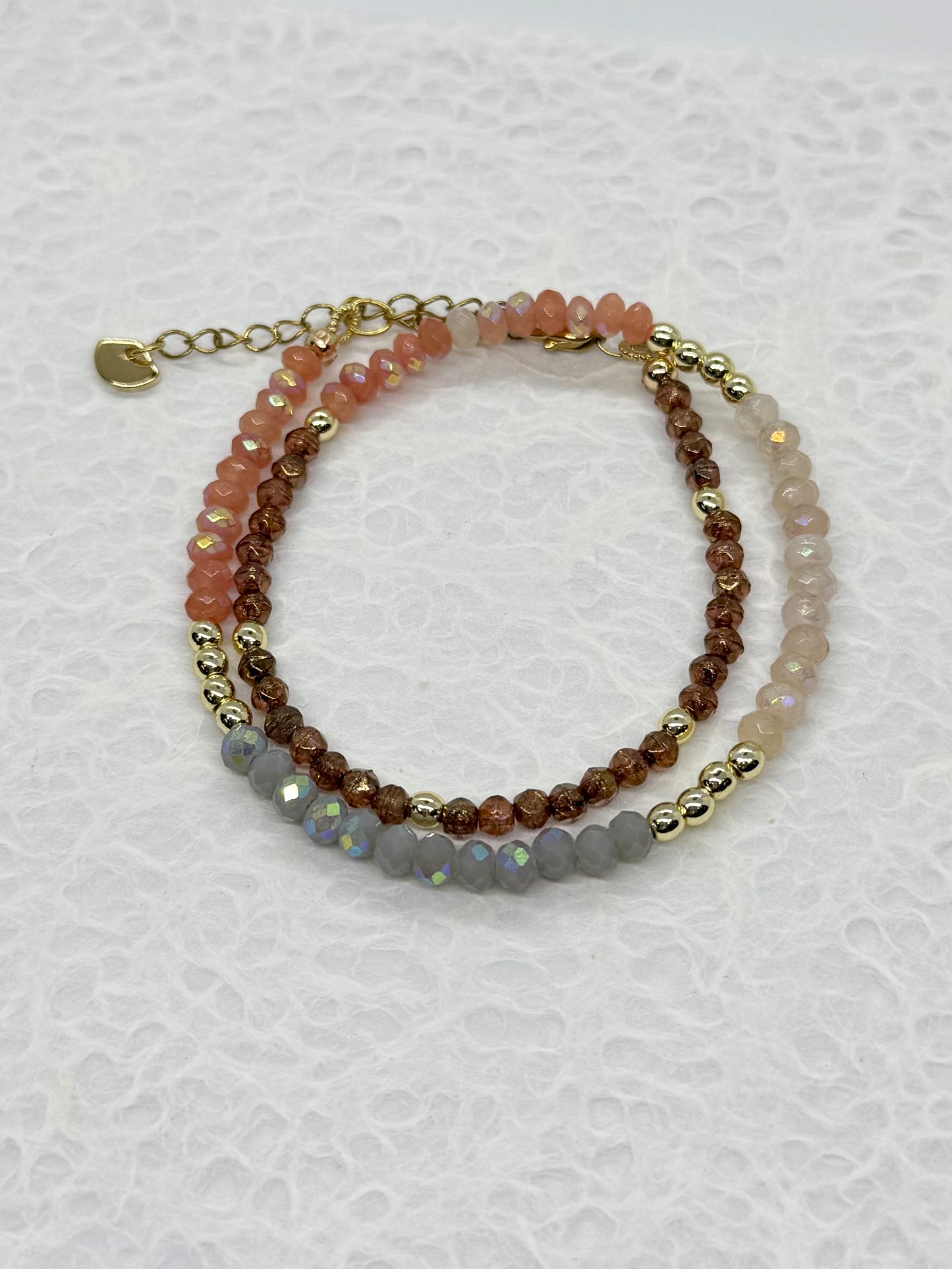 Stack of three beaded bracelets on a textured white surface