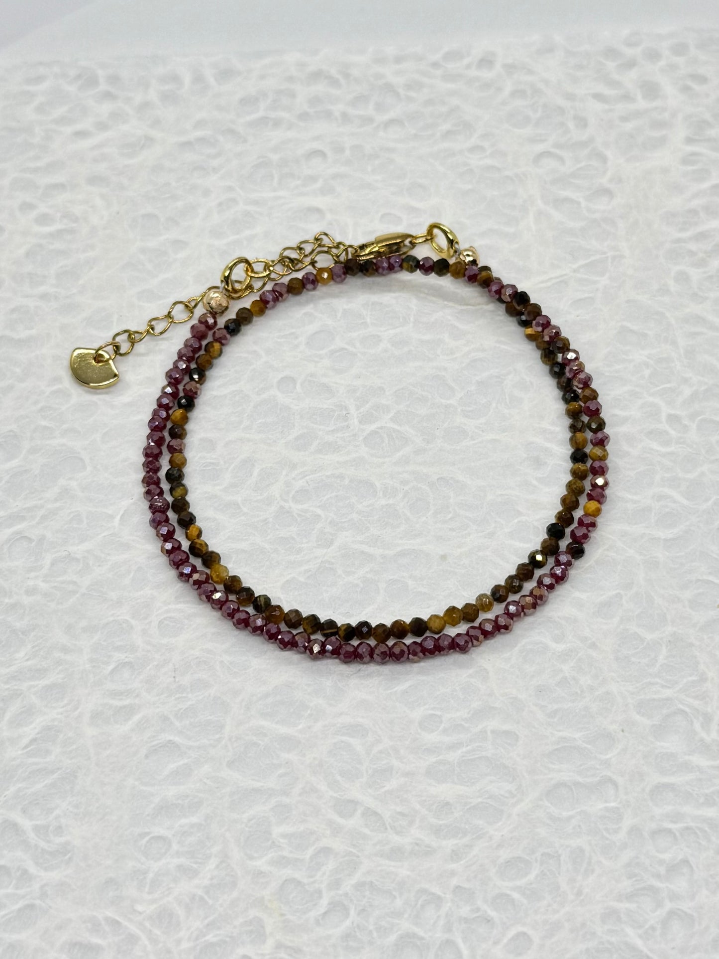 Beaded bracelet with gold clasp on a textured white background