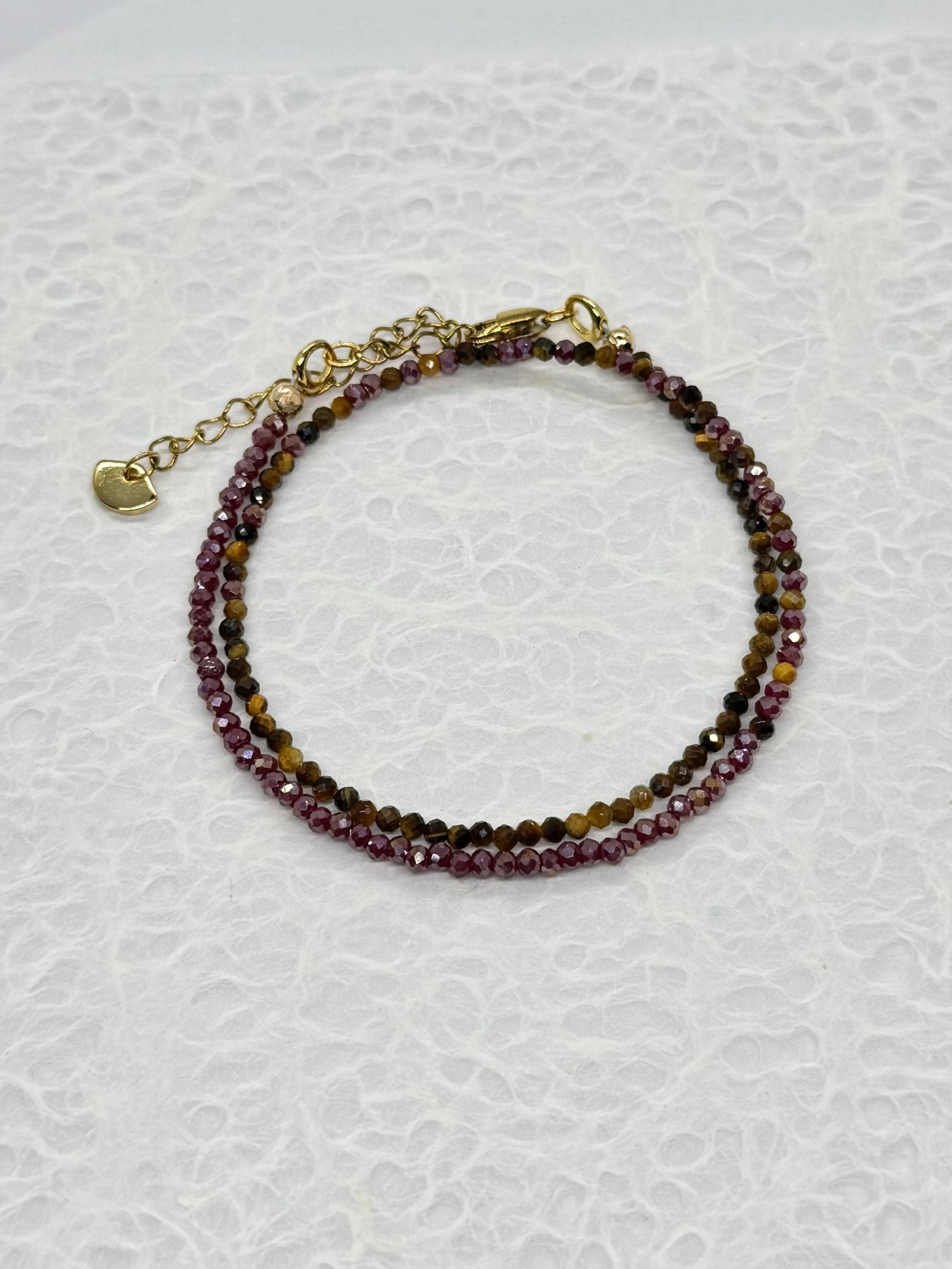 Beaded bracelet with gold clasp on a textured white background