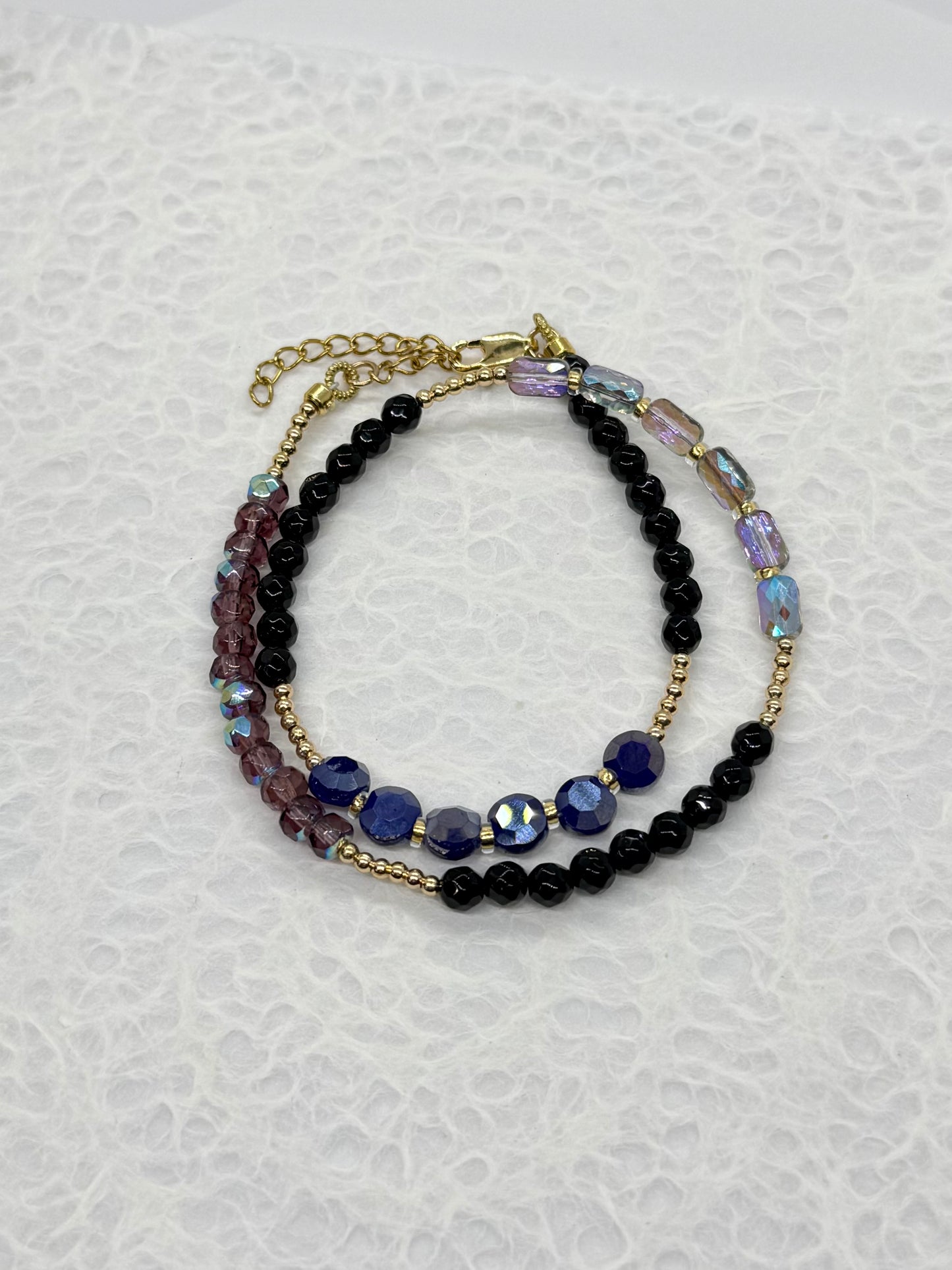 Stack of beaded bracelets on a textured white background
