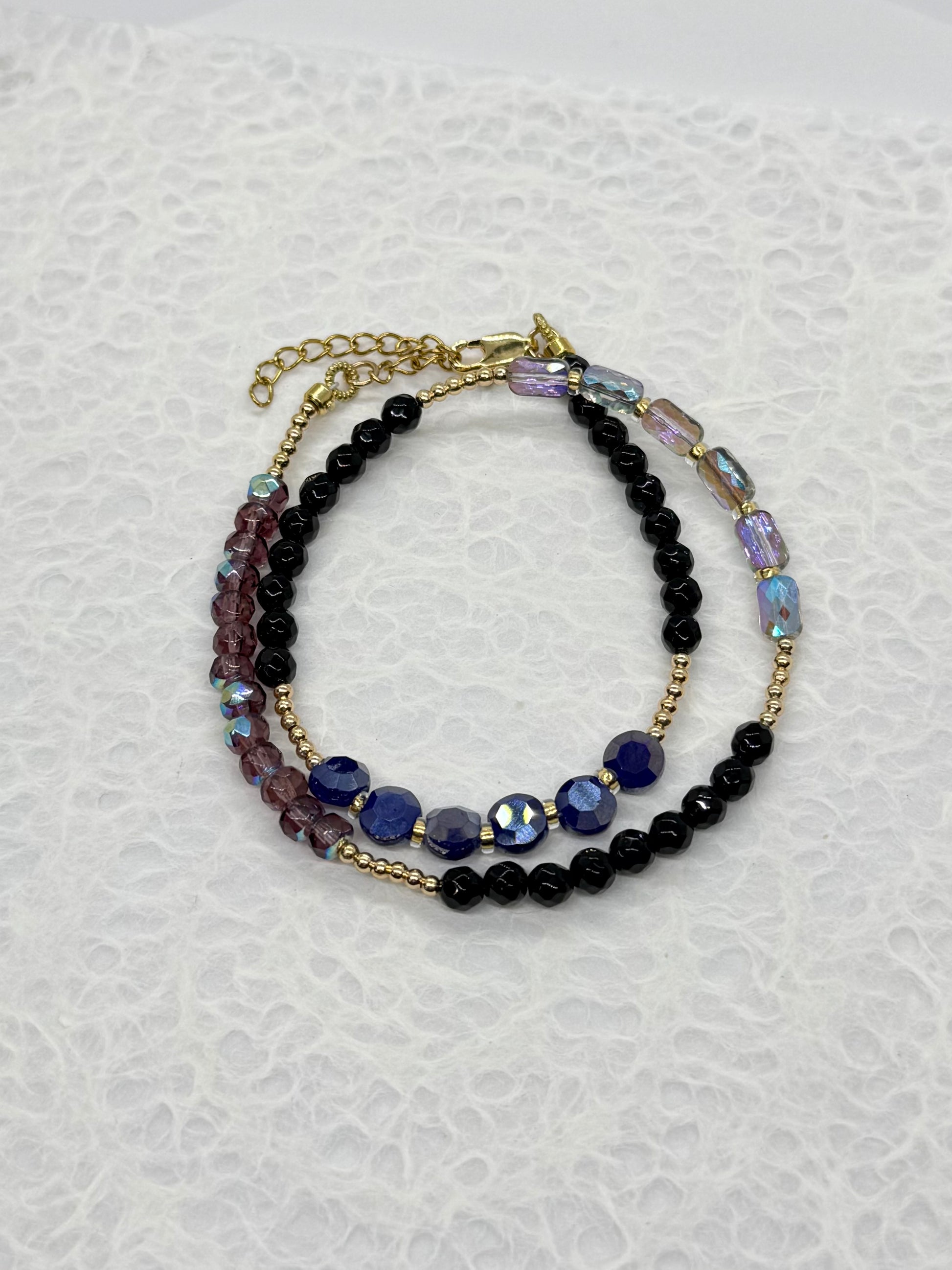 Stack of beaded bracelets on a textured white background