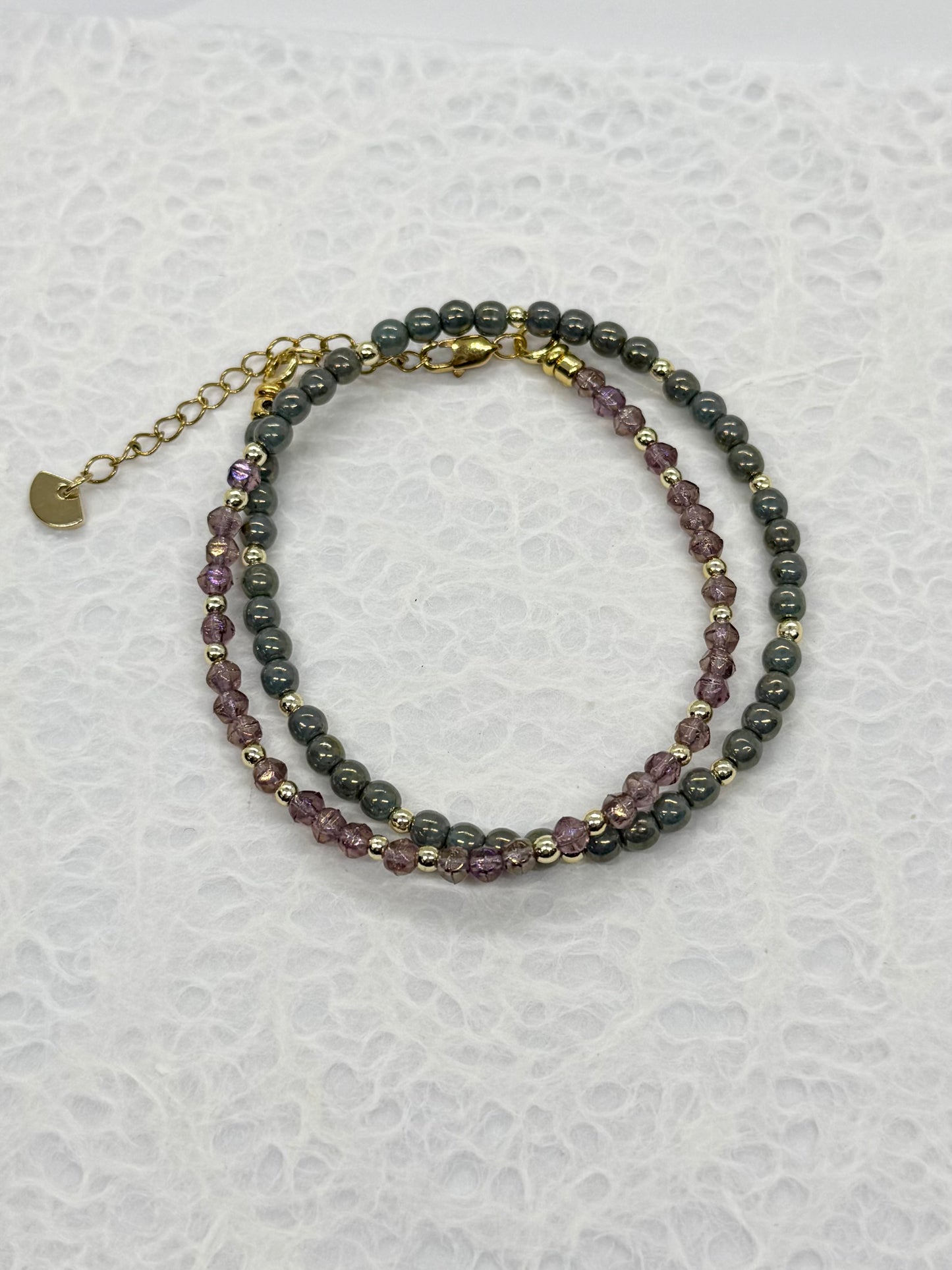 Two beaded bracelets on a textured white surface