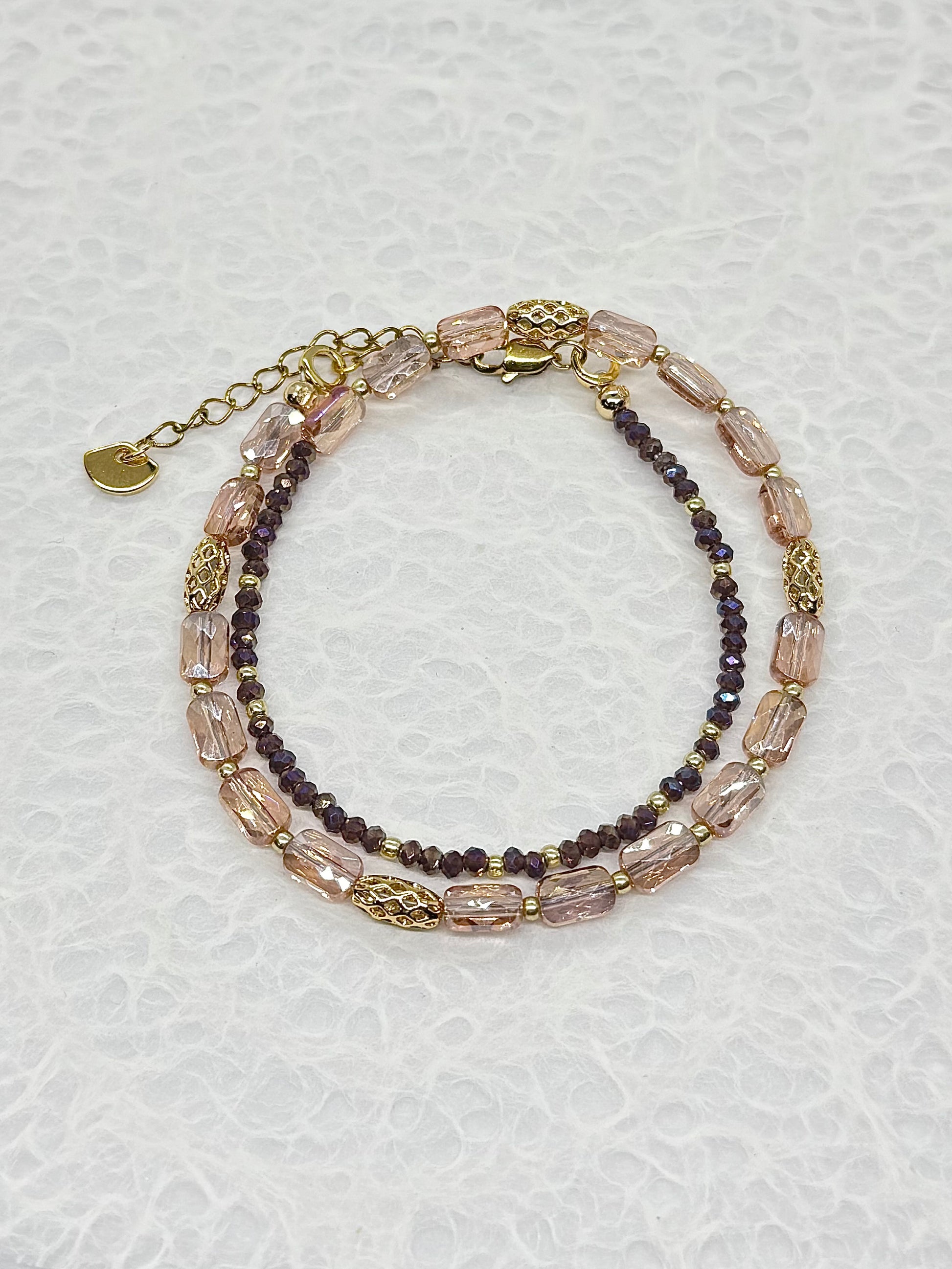 Two layered beaded bracelets on a textured white surface