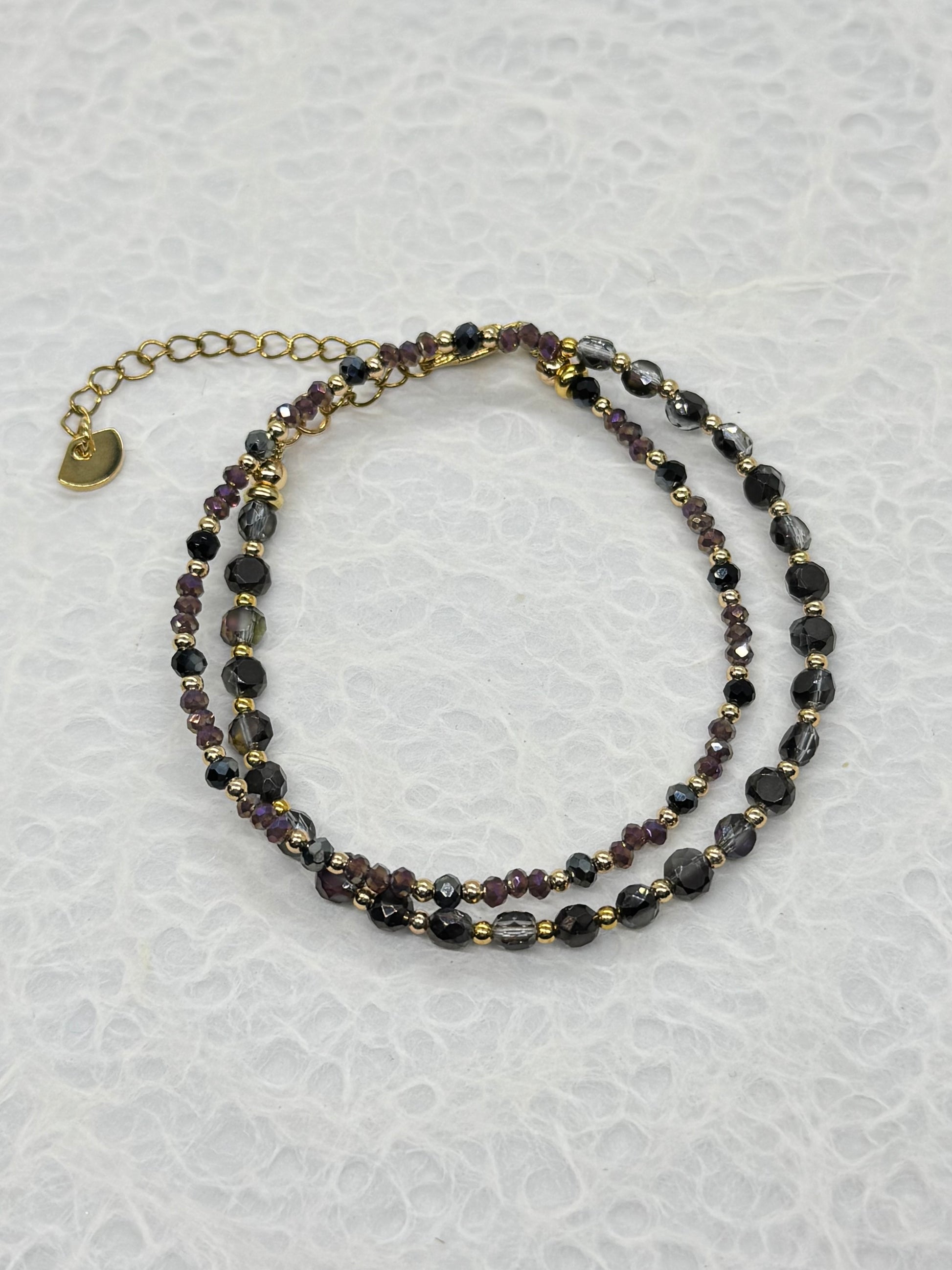 Two beaded necklaces on a textured white surface