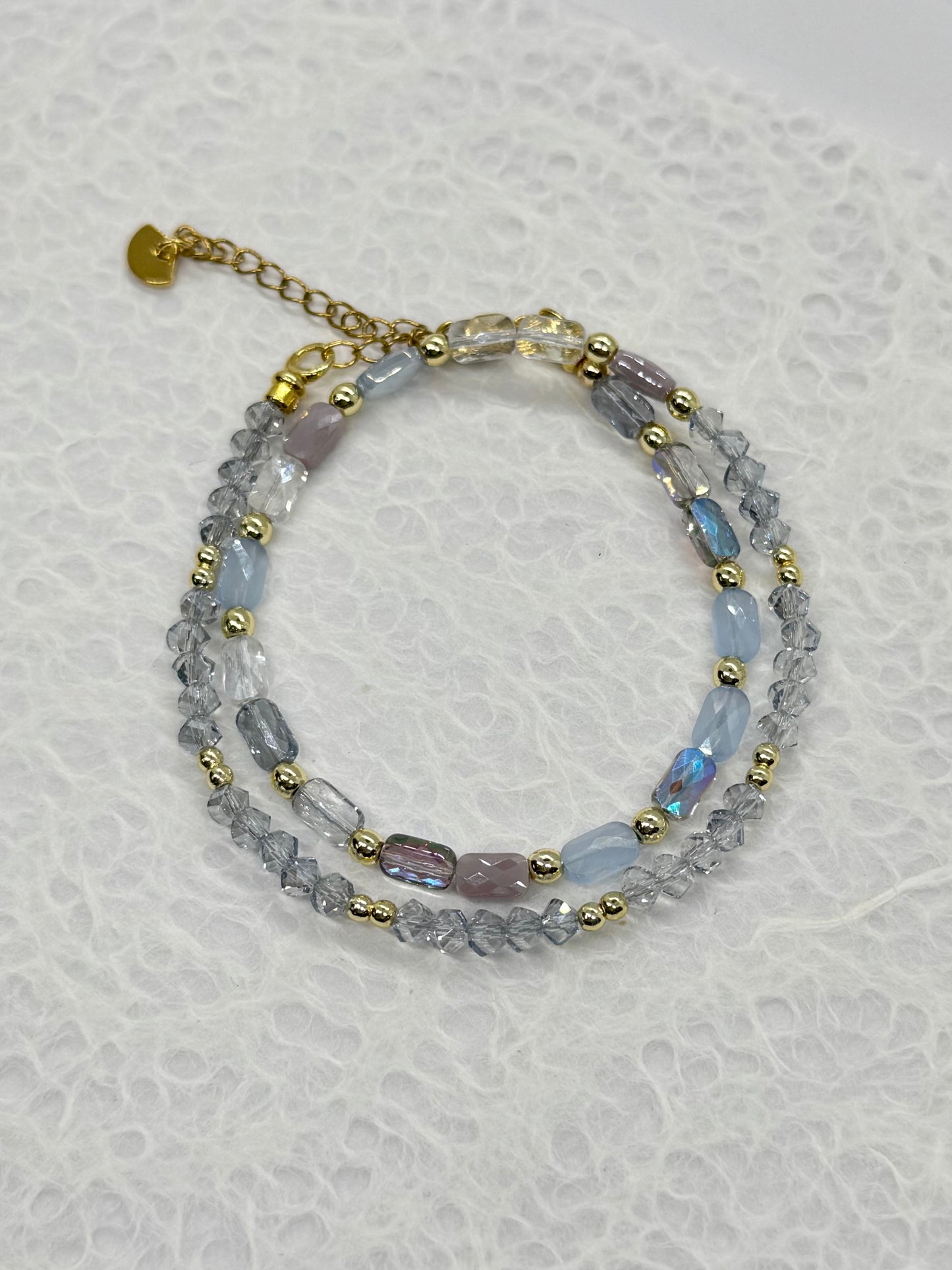 Multistrand beaded bracelet with gold accents on a textured white background