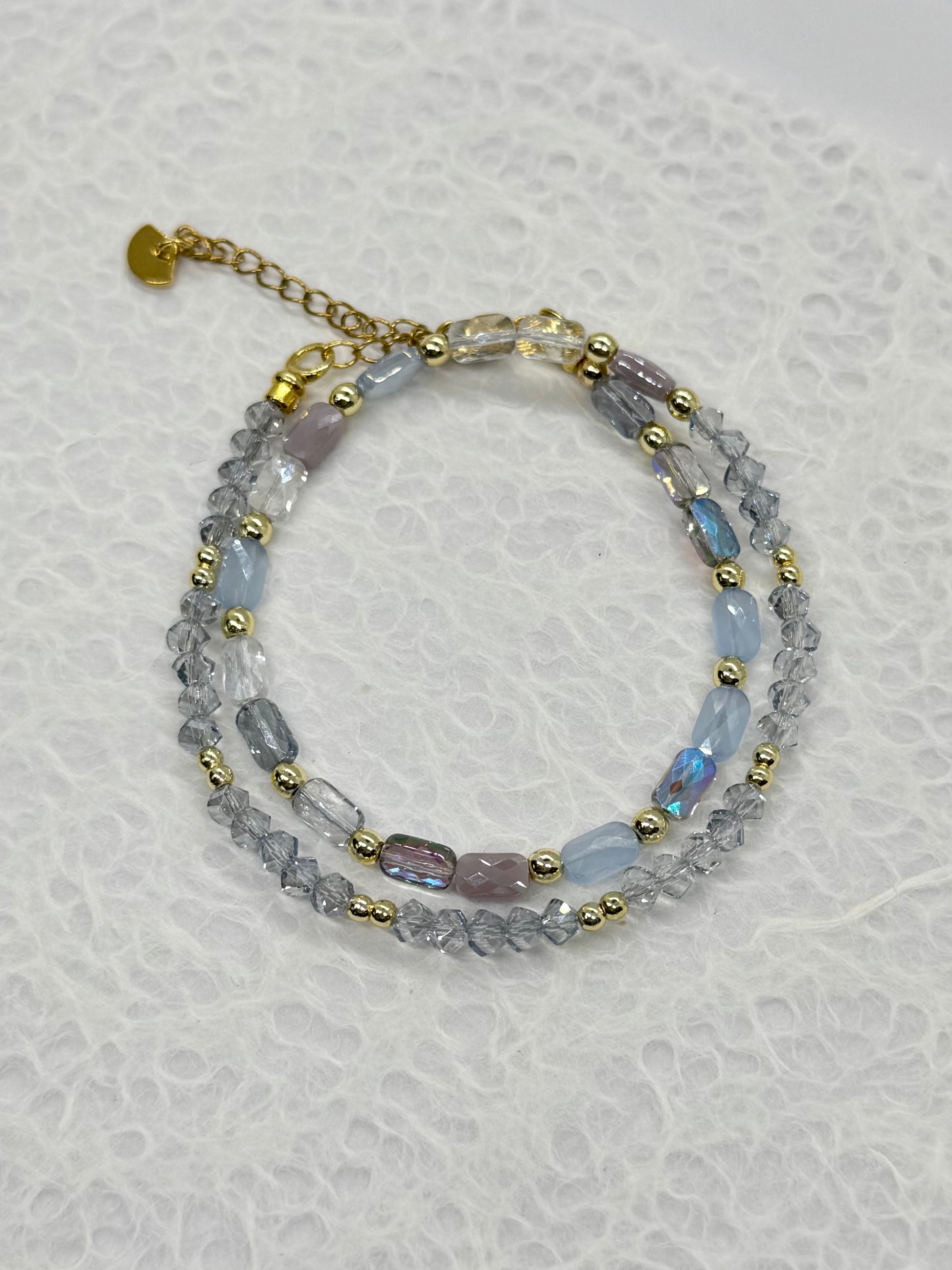 Multistrand beaded bracelet with gold accents on a textured white background